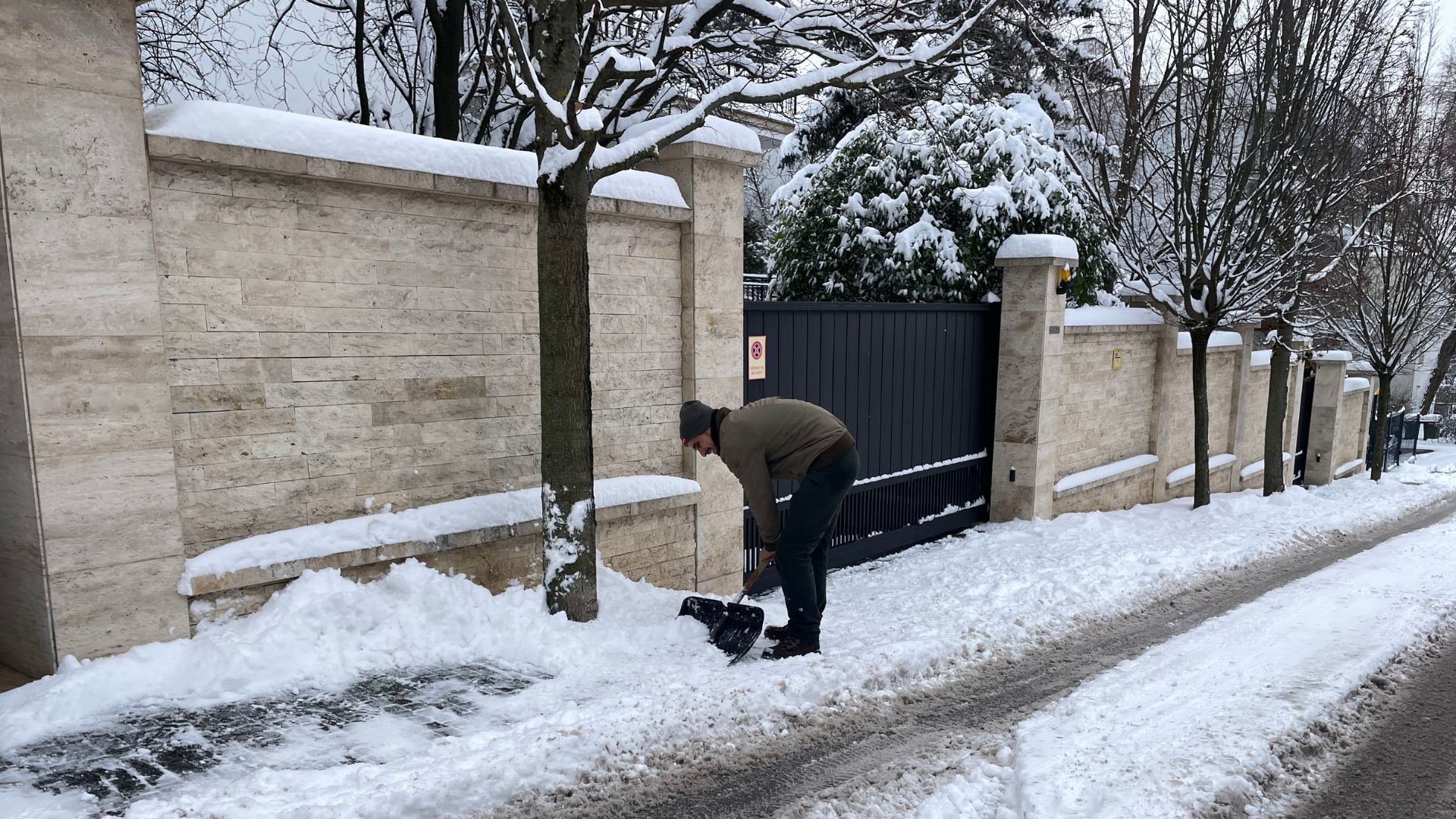 A man gamely tries to clear snow from the pavement.