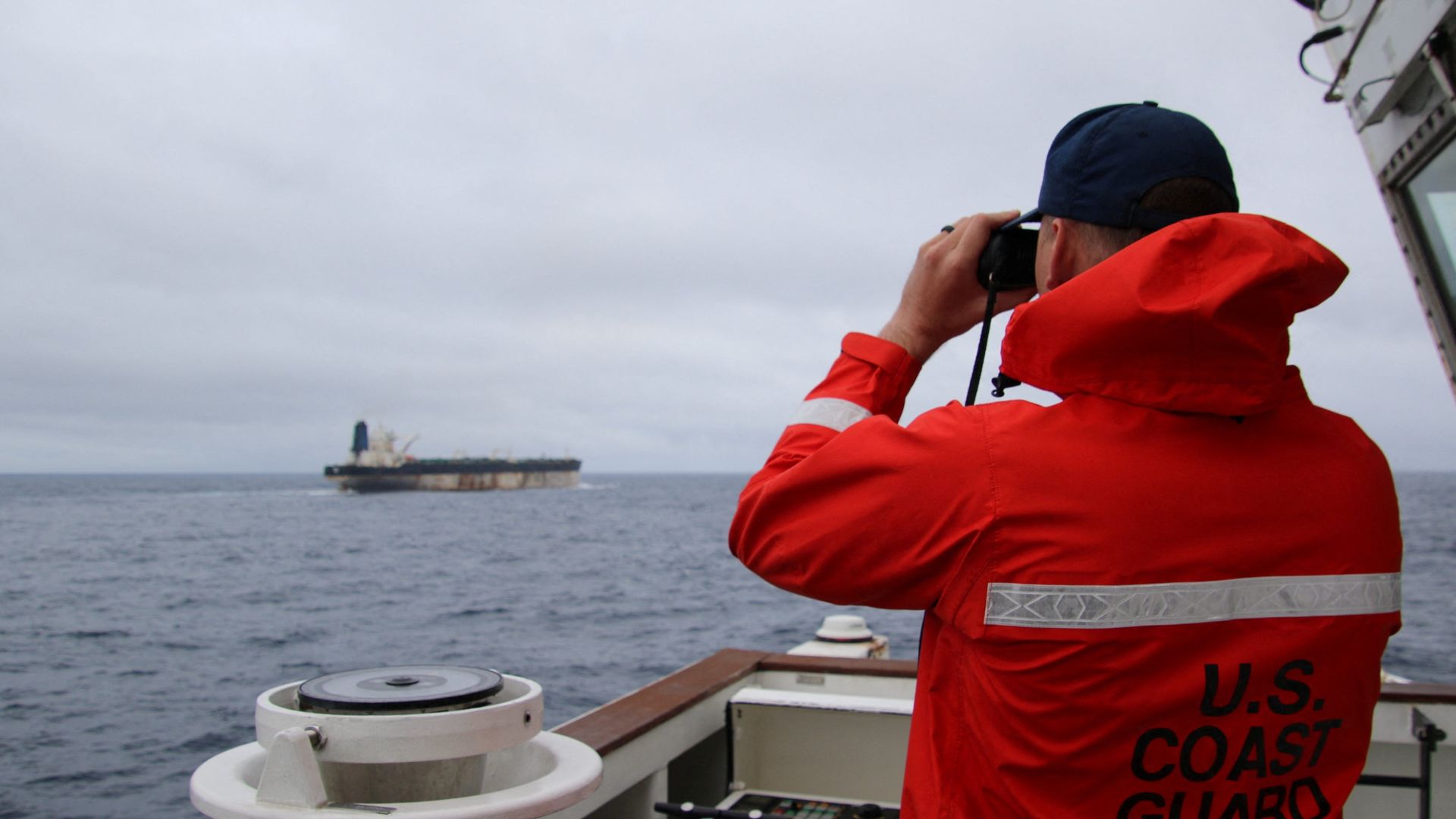 A US Coast Guard official looks through binoculars at the ship Marinera (formerly Bella 1) in this handout image released January 7, 2026. /US European Command via X/Handout