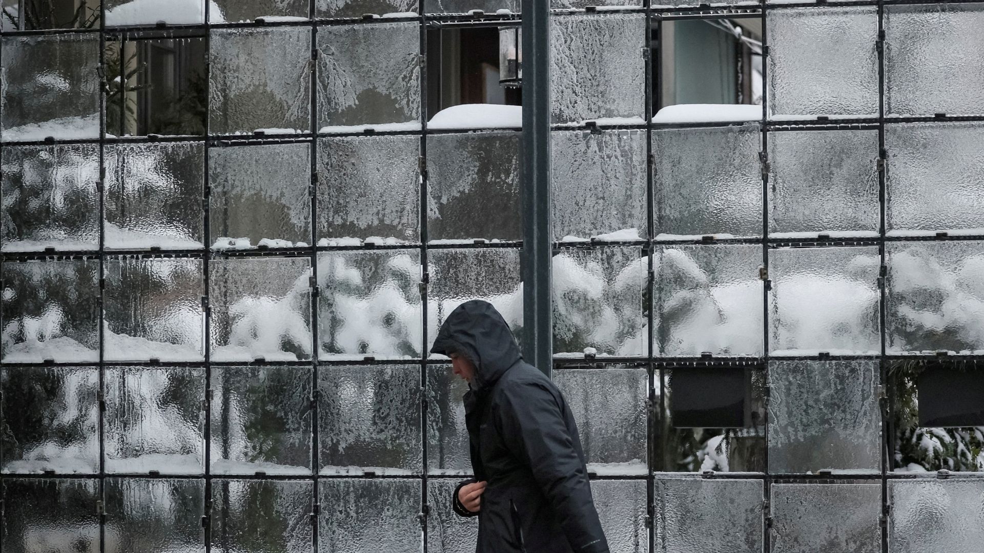 A man walks along a frozen glass of a restaurant's terrace wall on a frosty winter day. /Gleb Garanich/Reuters