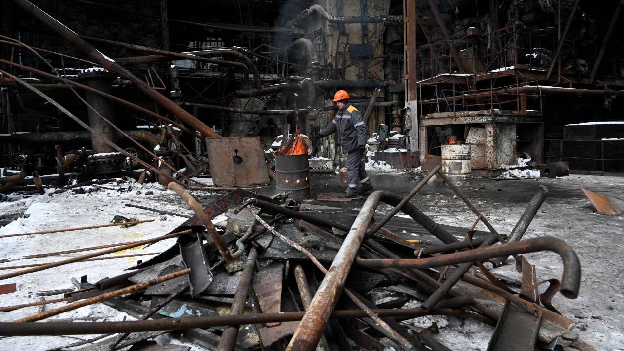An employee stokes a fire in a barrel at a power plant of Ukrainian energy provider DTEK, which was heavily damaged during air attacks. /Yuriy Dyachyshyn/AFP