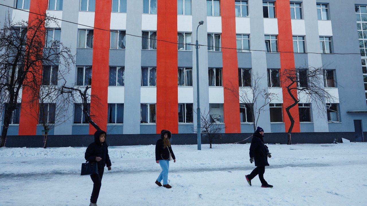 People walk in front of a school building in Kyiv that was damaged amidst a Russian drone attack on an apartment building nearby. /Valentyn Ogirenko/Reuters