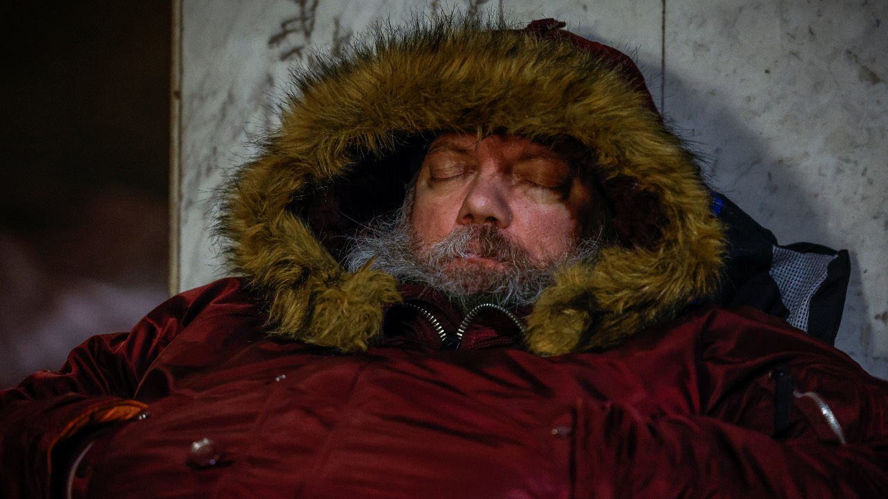 A man sleeps as he takes shelter inside a metro station during overnight missile and drone strikes by Russia, with temperatures falling below –20°C, in Kyiv, Ukraine. /Alina Smutko/Reuters