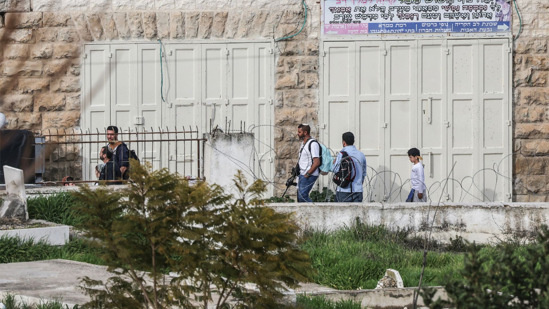 Armed Israeli settlers walk near the settlement of Abraham Avino in the Israeli-occupied West Bank city of Hebron on February 9. /Hazem Bader/AFP
