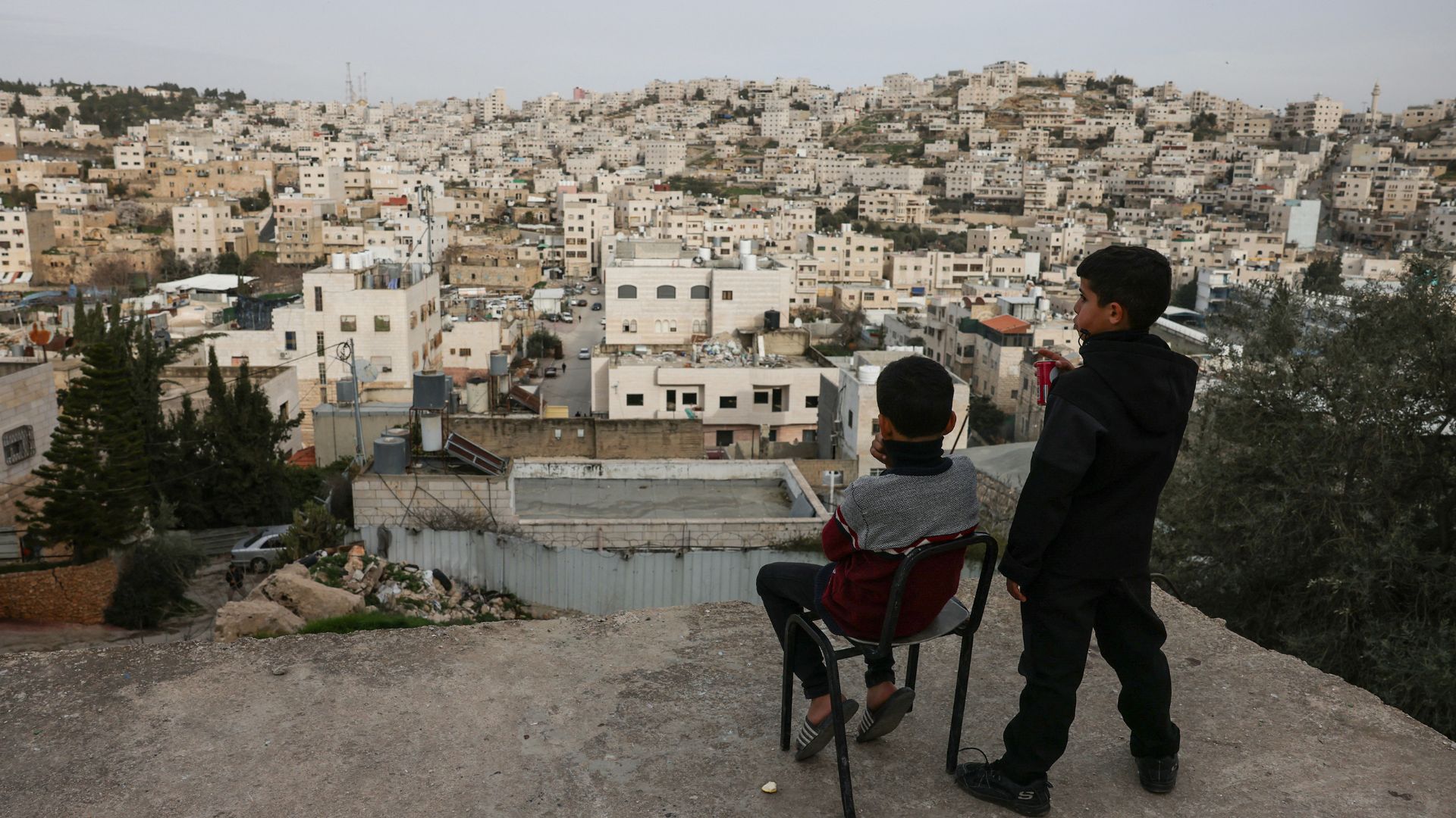  Palestinian boys look out over the Israeli-occupied West Bank city of Hebron from a rooftop on February 9. /Hazem Bader/AFP