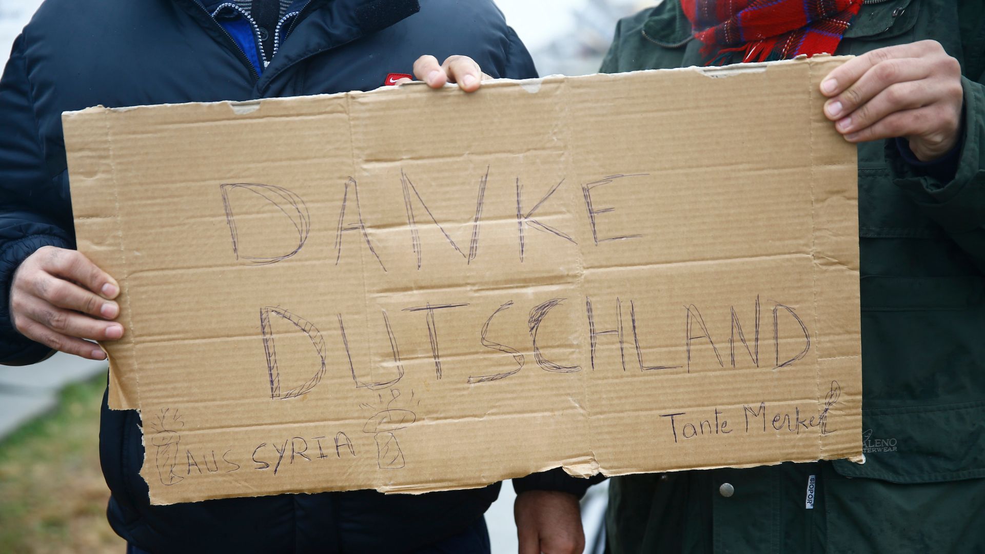 Migrants hold up a sign thanking Germany from Syria, at a temporary registration centre in the village of Schwarzenborn, northeast of Frankfurt, Germany October 15, 2015. /Kai Pfaffenbach/Reuters
