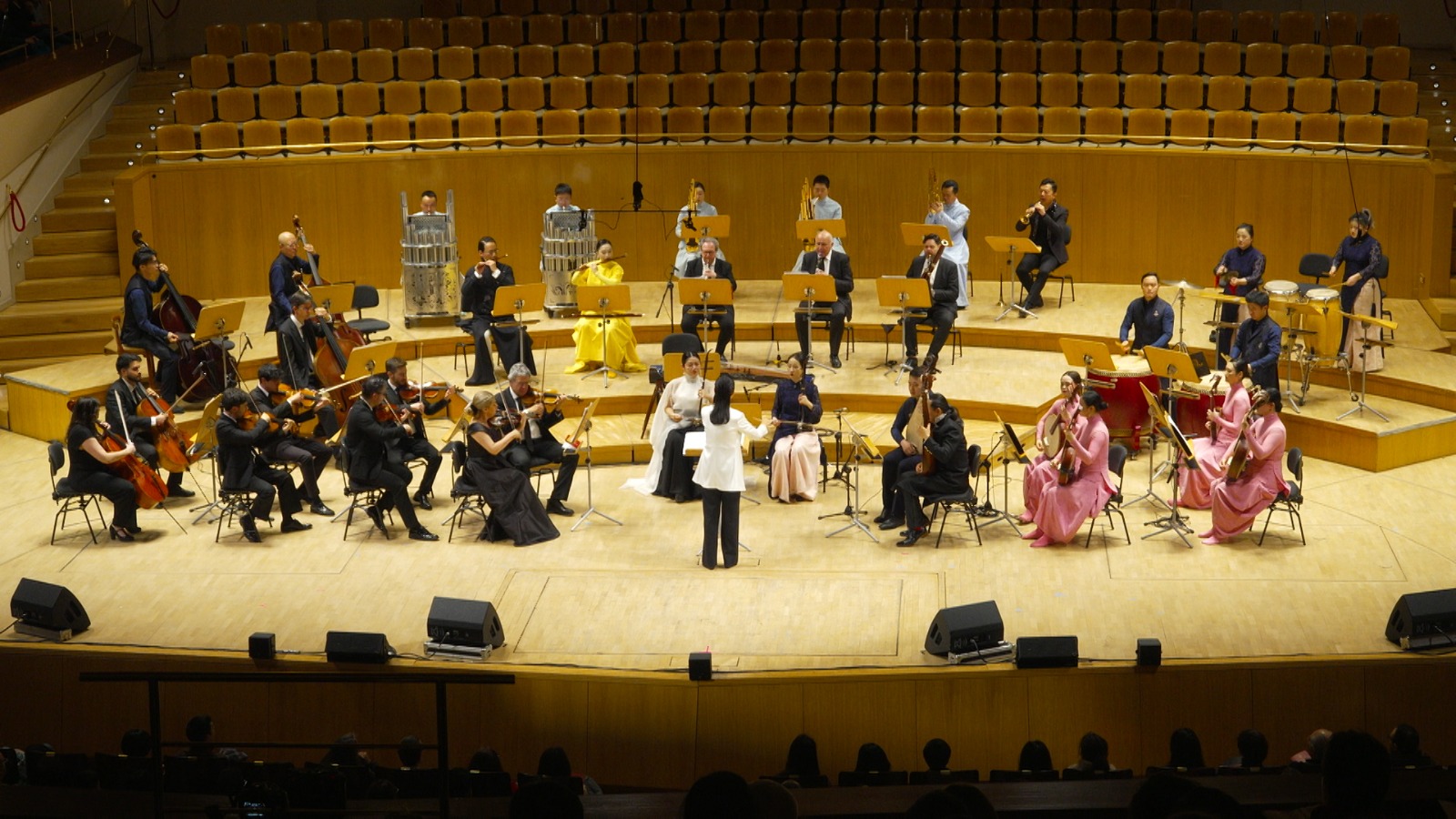 Shanghai Chinese Orchestra Conductor Peng Fei directs musicians playing Chinese instruments like the pipa and the erhu, along with Western violins and cellos. /CGTN