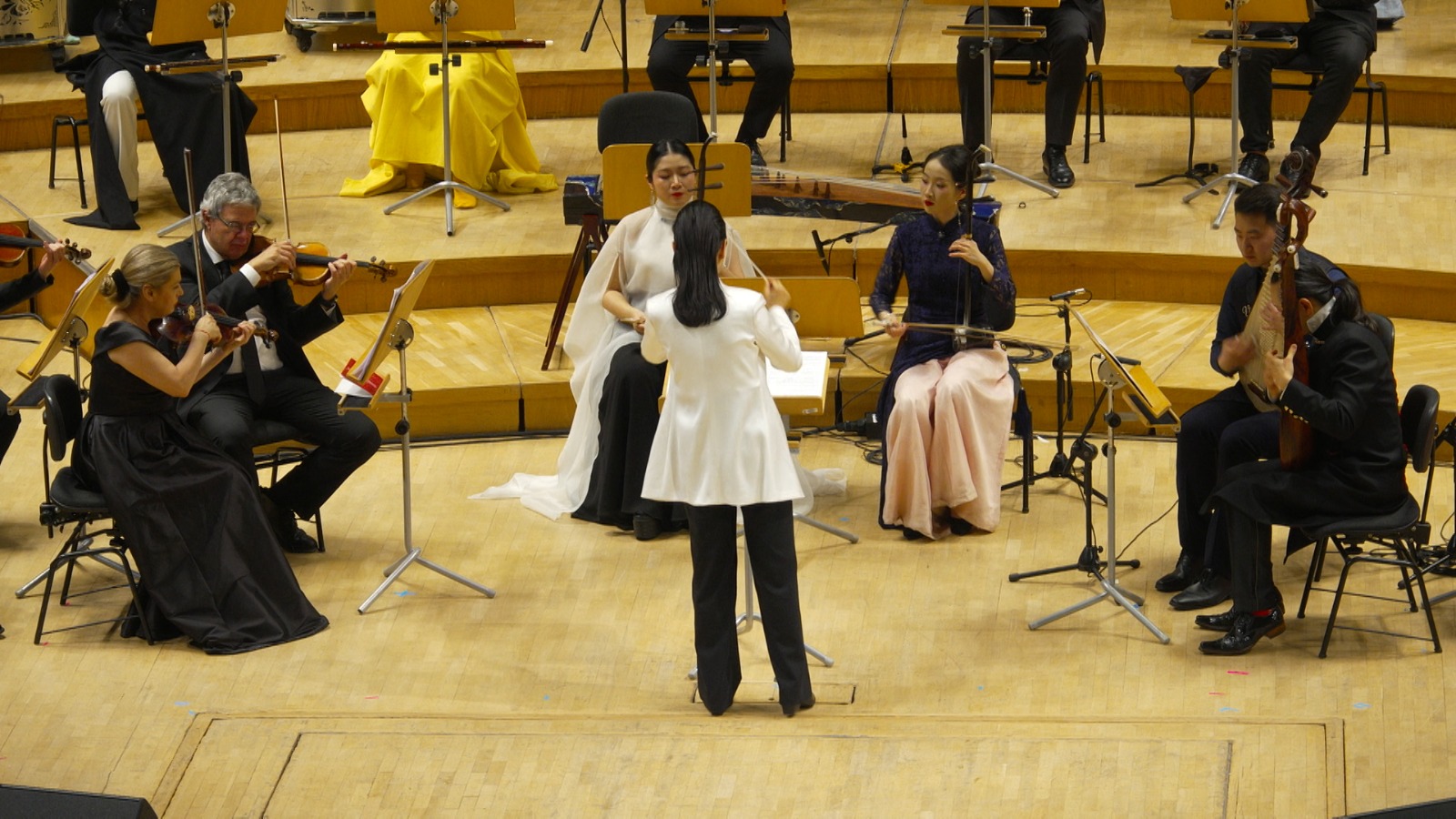 Shanghai Chinese Orchestra Conductor Peng Fei directs musicians playing Chinese instruments like the pipa and the erhu, along with Western violins and cellos. /CGTN