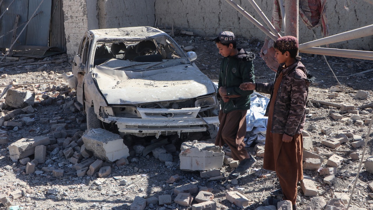 Afghan children walk past a damaged car after an overnight Pakistani airstrike at the Balish village in Urgun district, Paktika Province. /AFP