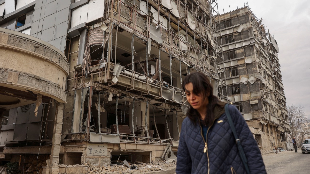 A woman walks past Tehran's Gandhi Hotel Hospital following an Israeli/US strike. /Majid Asgaripour/WANA/Reuters