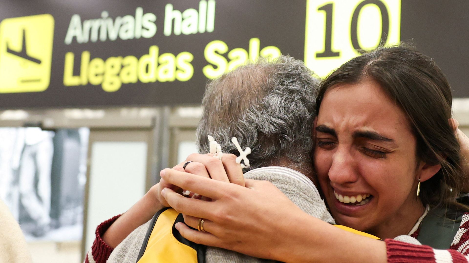 A woman reacts while embracing a man as Spanish citizens evacuated from Abu Dhabi arrive at Adolfo Suarez Madrid-Barajas airpor. /Violeta Santos Moura/Reuters
