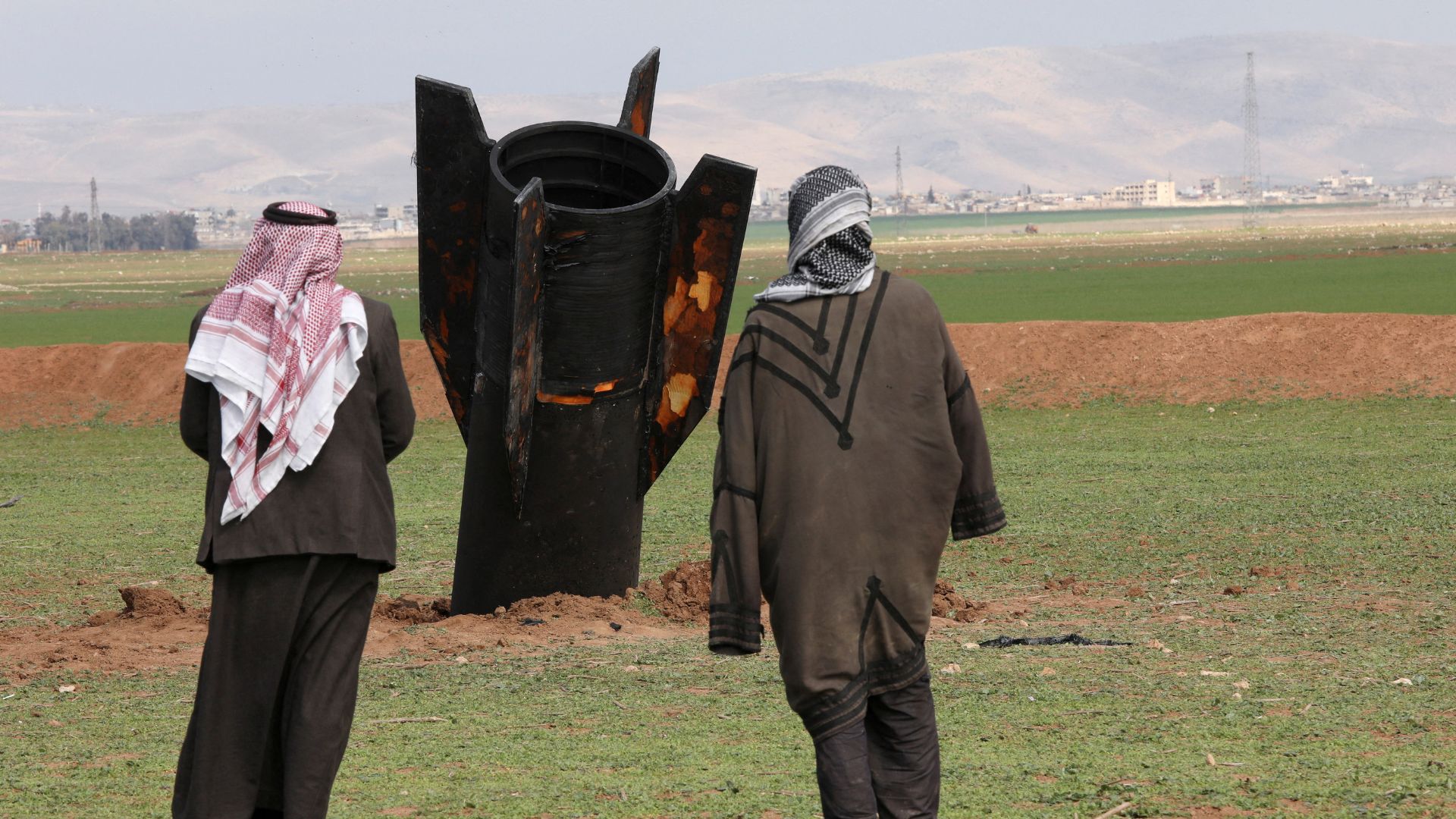 People stand next to a missile after it fell near Qamishli International Airport, amid the U.S.-Israeli conflict with Iran, in Qamishli, Syria. /Orhan Qereman/Reuters