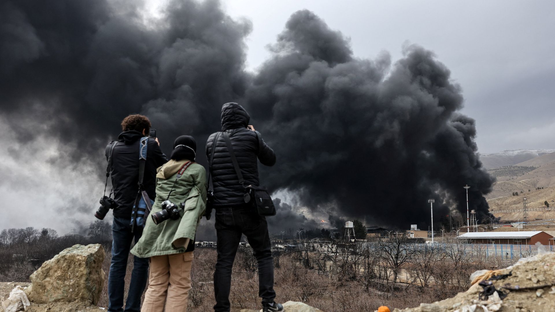 Onlookers record smoke rising after a reported strike on Shahran fuel tanks, amid the US-Israeli conflict with Iran, in Tehran on March 8, 2026. /Majid Asgaripour/WANA