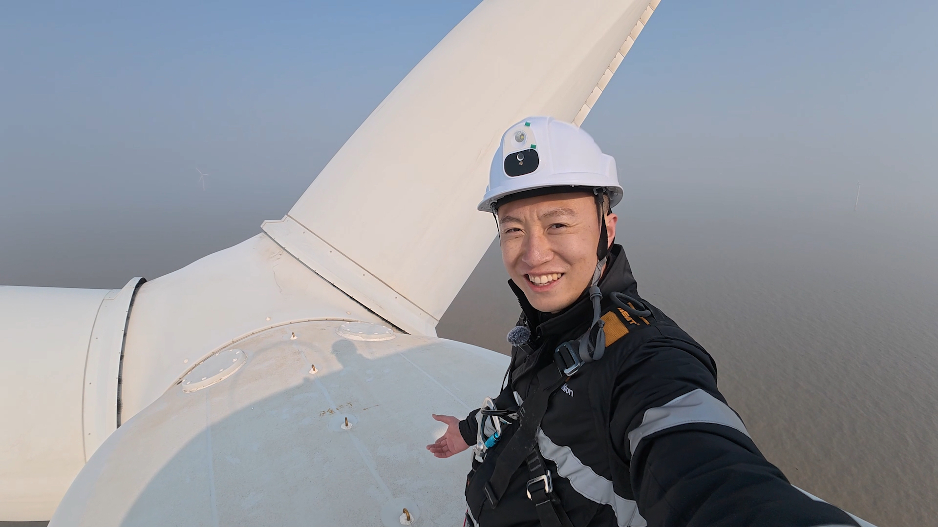 Hanging on for dear life, CGTN's Wang Tianyu says hello atop a towering turbine. /CGTN