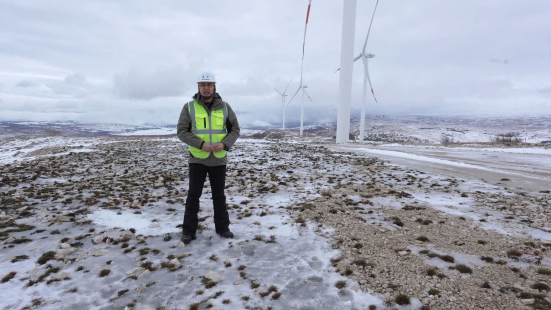 CGTN reporter Aljoša Milenković stands on the new wind farm in Ivovik, Bosnia. /CGTN