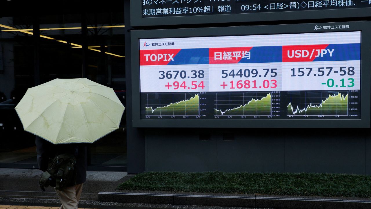 A pedestrian looks at a stock quotation board showing the Topix average, the Nikkei share average and the exchange rate between Japanese yen and U.S. dollar outside a brokerage in Tokyo. /Kim Kyung-Hoon/Reuters
