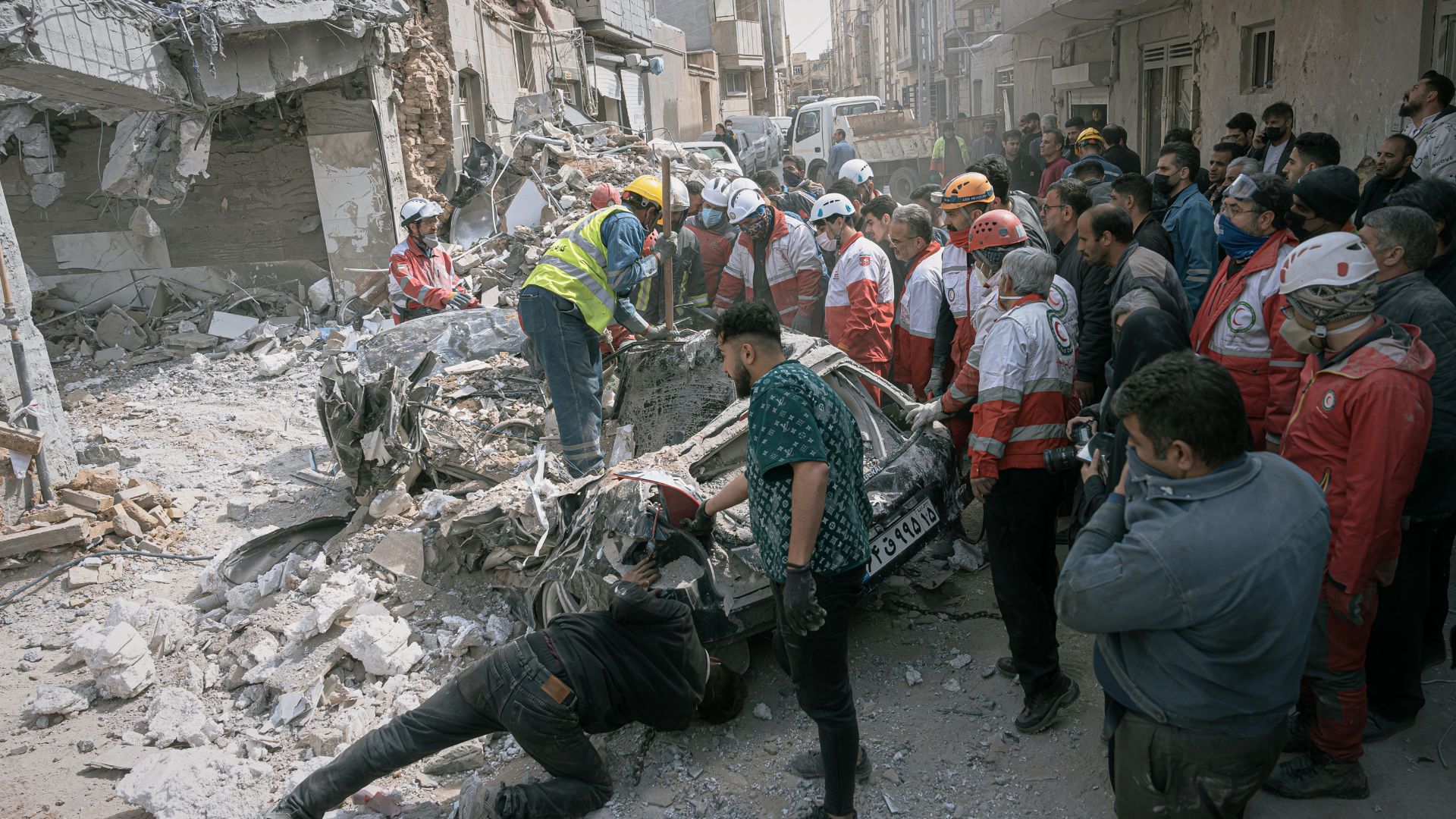 First responders inspect a destroyed car at the site of a residential building hit in an overnight strike during the US-Israeli military campaign in Tabriz, East Azerbaijan Province, northwestern Iran, Tuesday, March 24, 2026. /AP Photo/Matin Hashemi/
