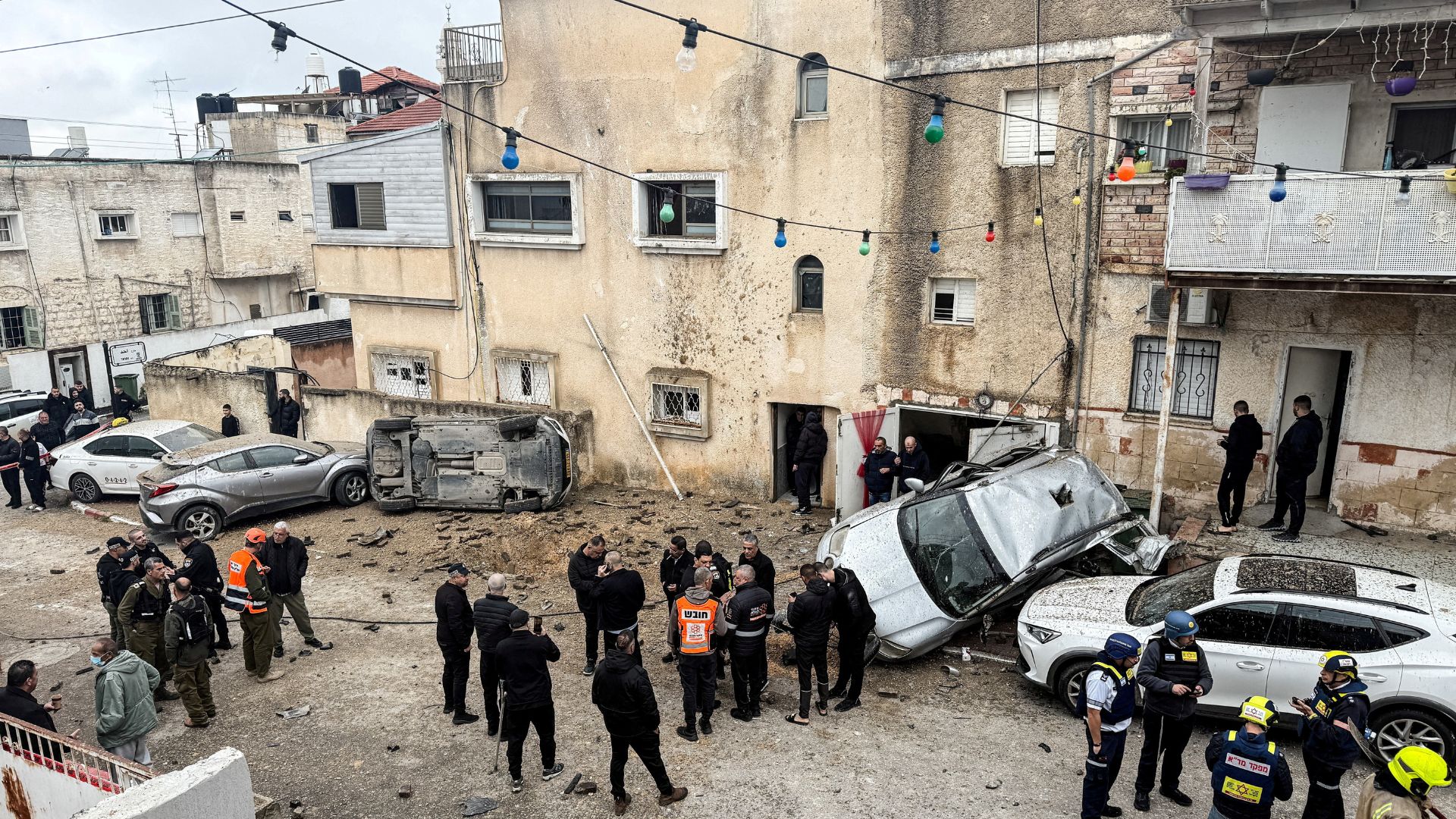 Members of the Israeli emergency services, security officials and onlookers gather at a missile impact site. /Rami Amichay/Reuters
