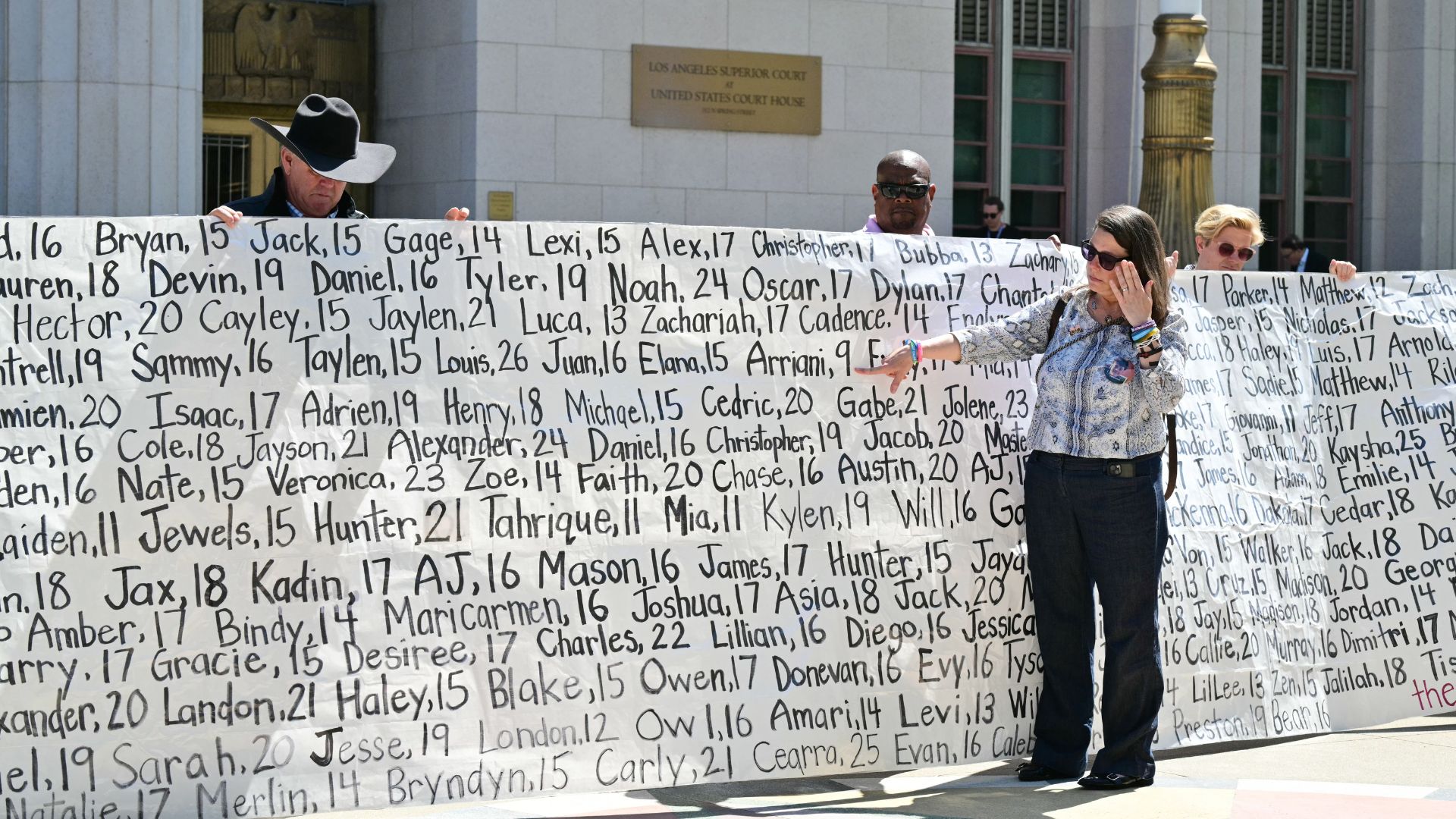 Mary Rodee, whose 15-year-old son died by suicide, points to a banner listing victims’ names outside Los Angeles Superior Court after the social media trial verdict, on March 25 that found Meta and YouTube liable for harming a young woman through the addictive design of their social media platforms. /Frederic J. Brown/AFP
