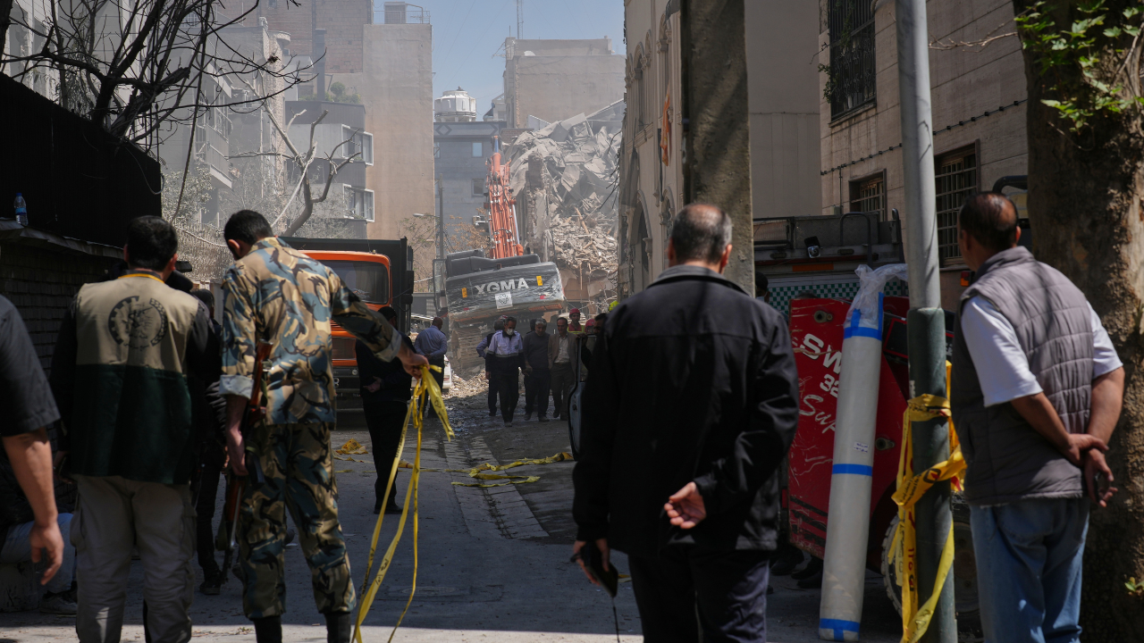 Bystanders watch from a distance as rescue teams and first responders work at the site of a strike that, according to a security official at the scene, destroyed half of the Khorasaniha Synagogue and nearby residential buildings in Tehran, Iran, Tuesday, April 7, 2026. /AP Photo/Francisco Seco