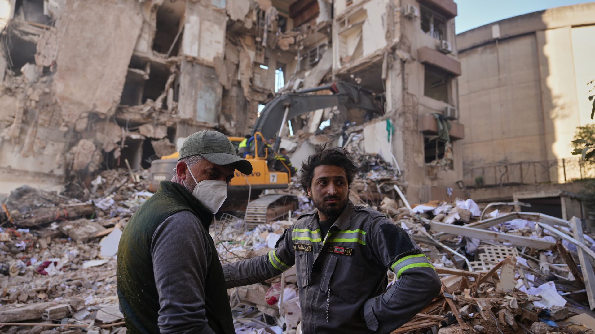 A Lebanese civil defense worker, right, stands with a resident at the site of a building destroyed in an Israeli airstrike a day earlier in central Beirut on April 9. /Hassan Ammar/AP