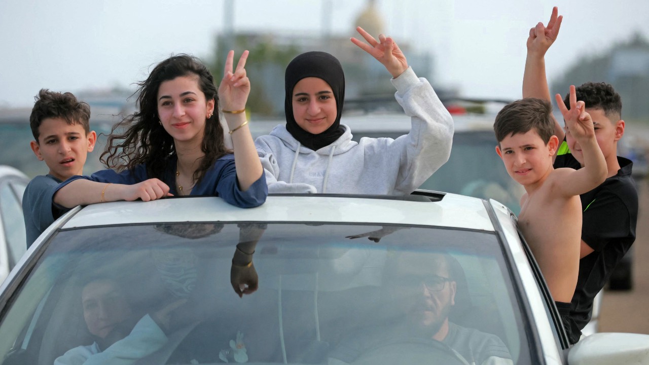 Displaced residents travel through the Qasmieh area as they flash victory signs on the way back to their homes in southern Lebanon. /Ibrahim Amro/AFP