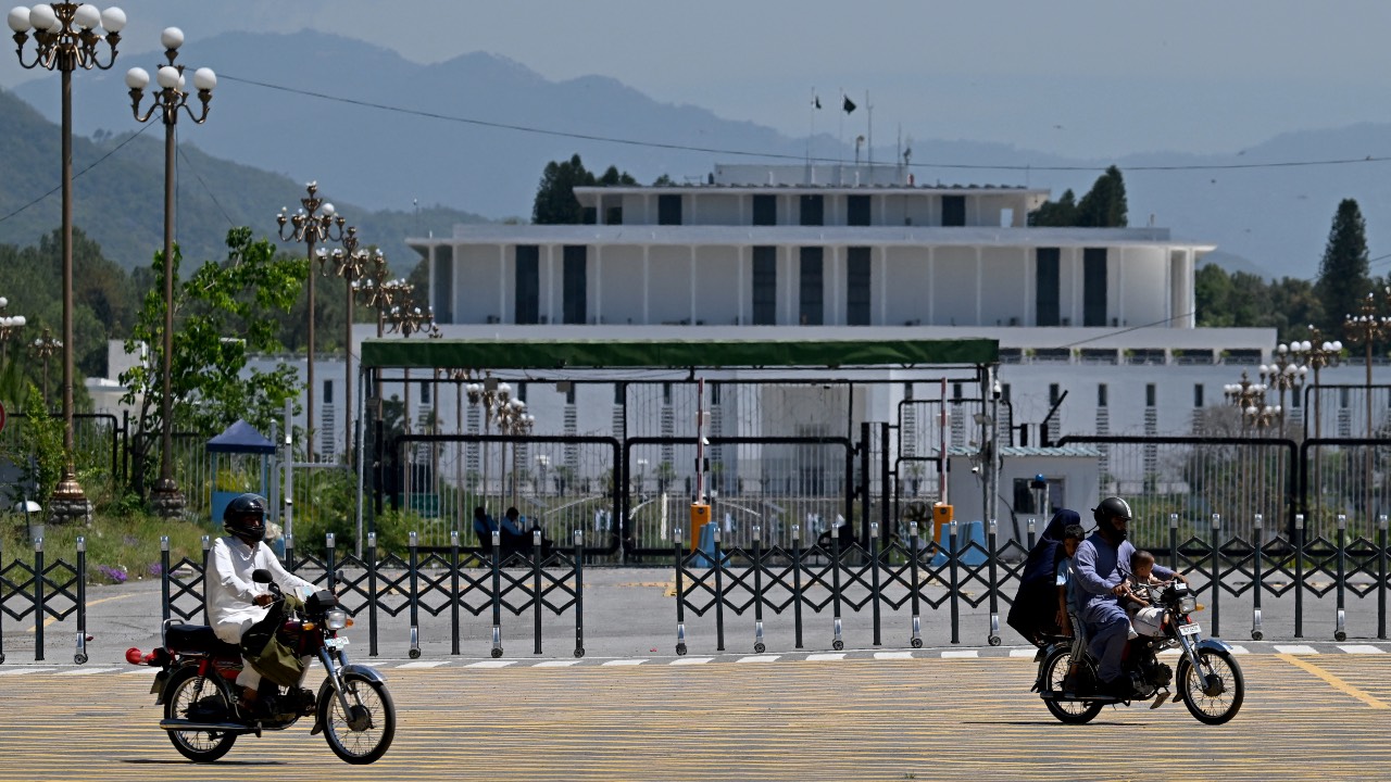 Commuters ride past the President House at the Red Zone area in Islamabad after authorities lifted the heightened security and restrictions imposed in the area ahead of anticipated US-Iran peace talks. /Aamir Qureshi/AFP