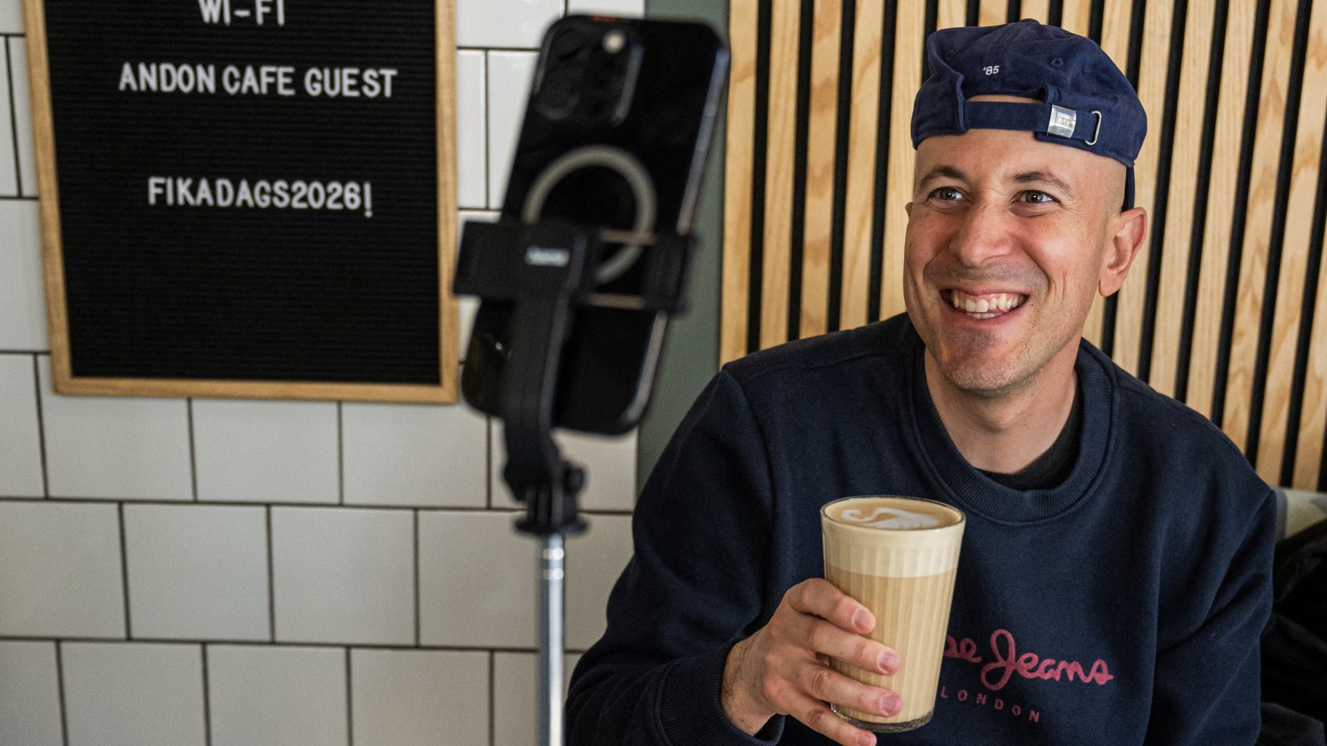 Andreu Vizquerra, a tourist from Spain, takes a photo of himself with a latte ordered via the AI assistant 'Mona' at the Andon Café in Stockholm. /Jonathan Nackstrand/AFP
