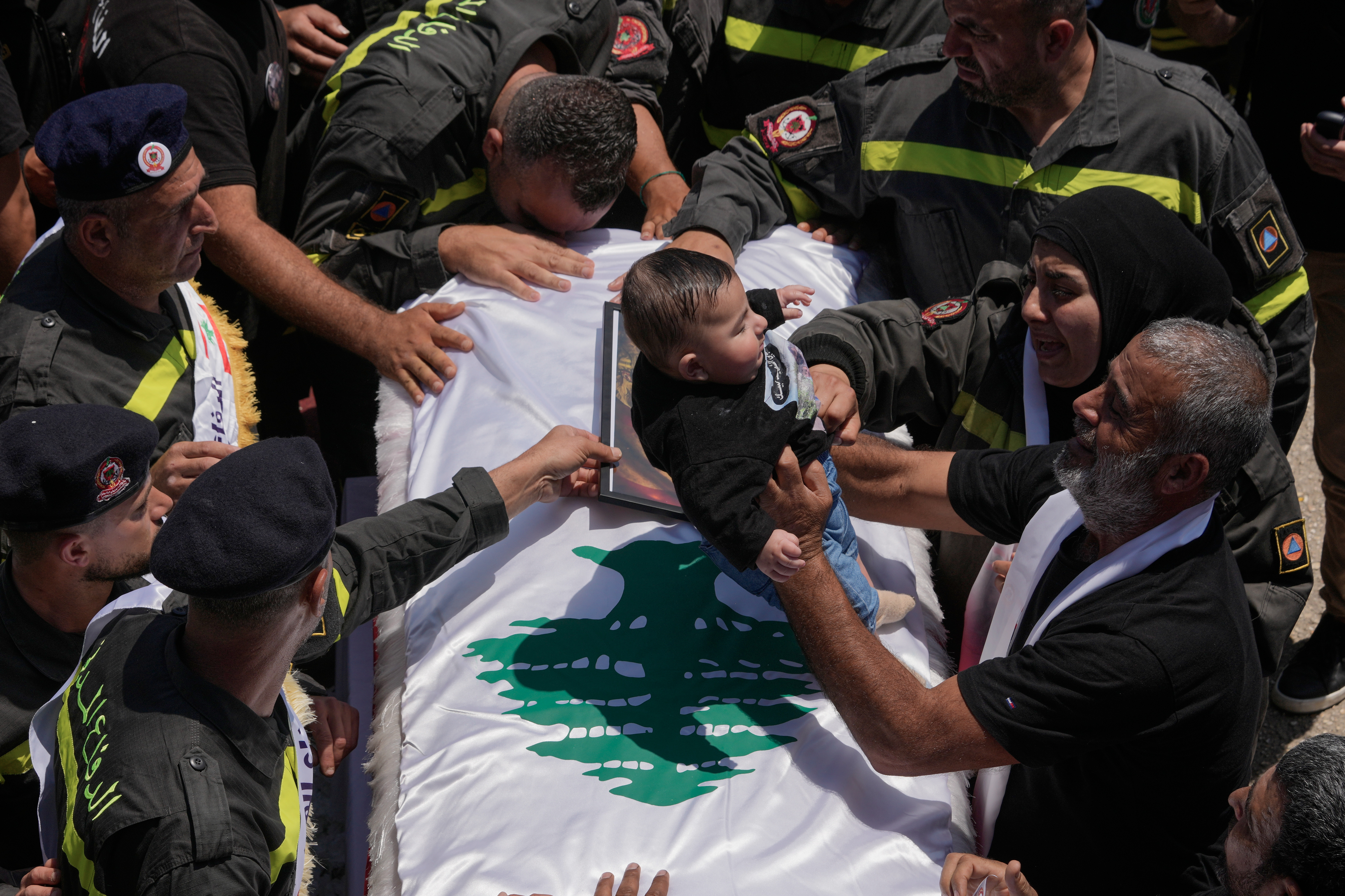 A five-month-old boy is placed on the coffin of his father – Lebanese Civil Defense worker Hussein Ali Satti, who was killed alongside two colleagues in an Israeli strike on Tuesday – during his funeral procession in Tyre, Lebanon. /Hussein Malla/AP