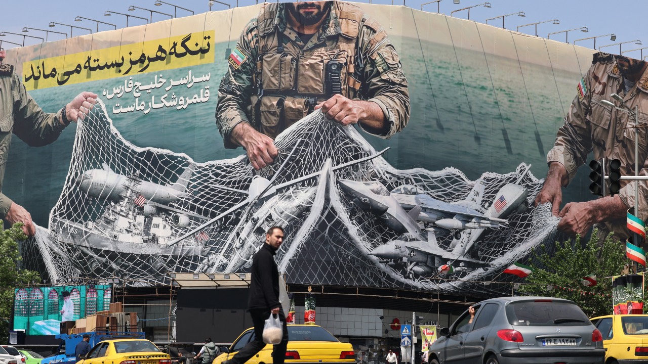 Vehicles drive past a giant billboard reading 'The Strait of Hormuz remains closed' at the Revolution Square in Tehran. /Atta Kenare/AFP
