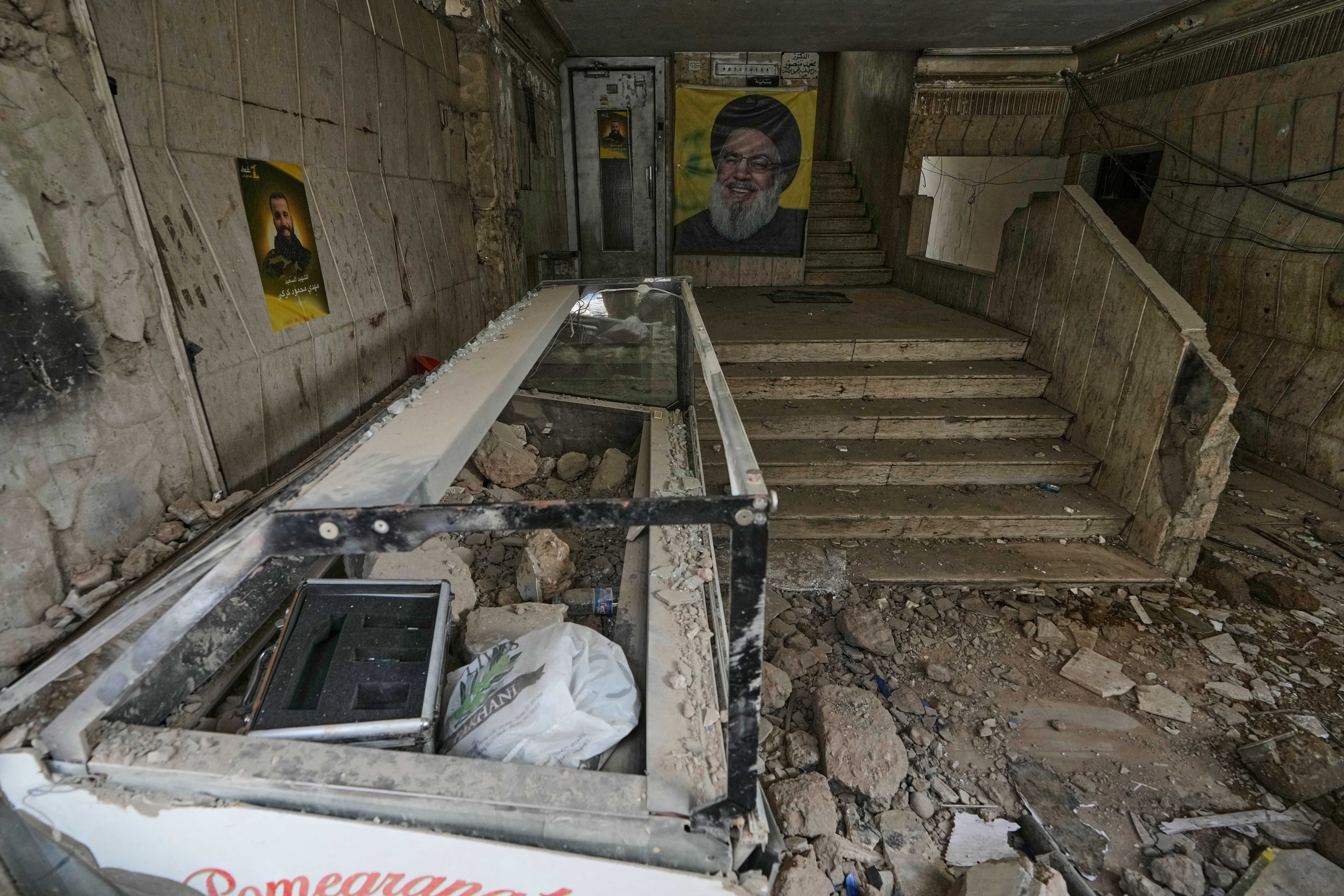 A portrait of the late Hezbollah leader Sayyed Hassan Nasrallah, center, hangs at the entrance of a building damaged in an Israeli airstrike in Dahiyeh, Lebanon. /Bilal Hussein/AP