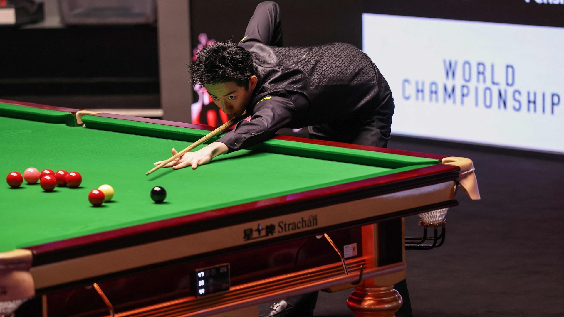 Wu attempts to pot a red during the final. /Darren Staples /AFP