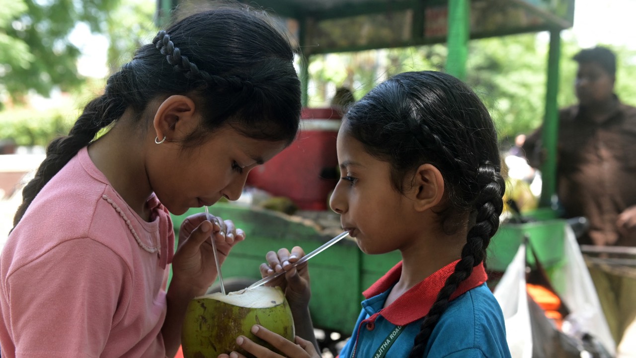 Children drink coconut water on a hot summer day along a street in Amritsar, India. /Narinder Nanu/AFP