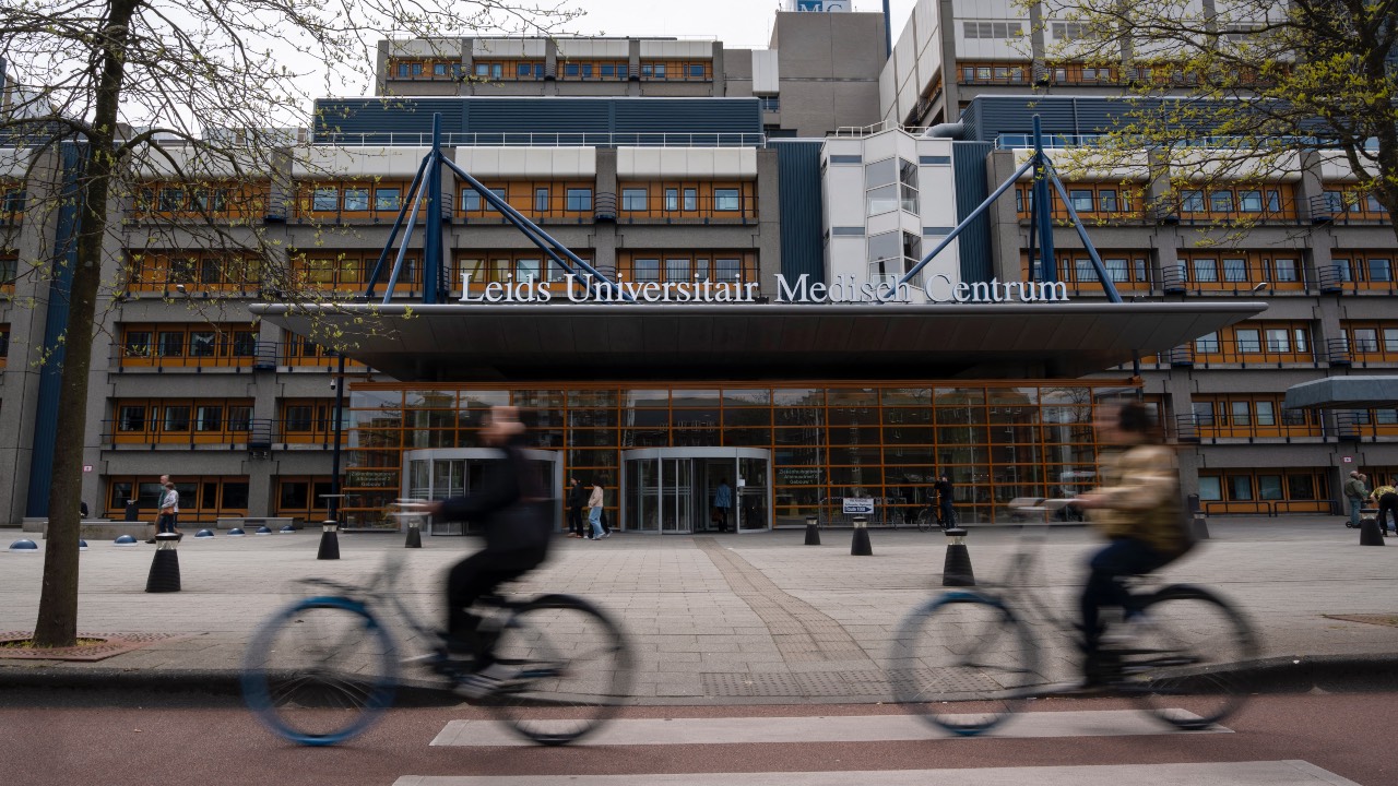 People ride bicycles in front of the main entrance of the Leiden University Medical Center (LUMC) hospital in Leiden, as the Netherlands wait the possible arrival of people evacuated from a cruise ship hit with a deadly outbreak of hantavirus. /Lina Selg/AFP