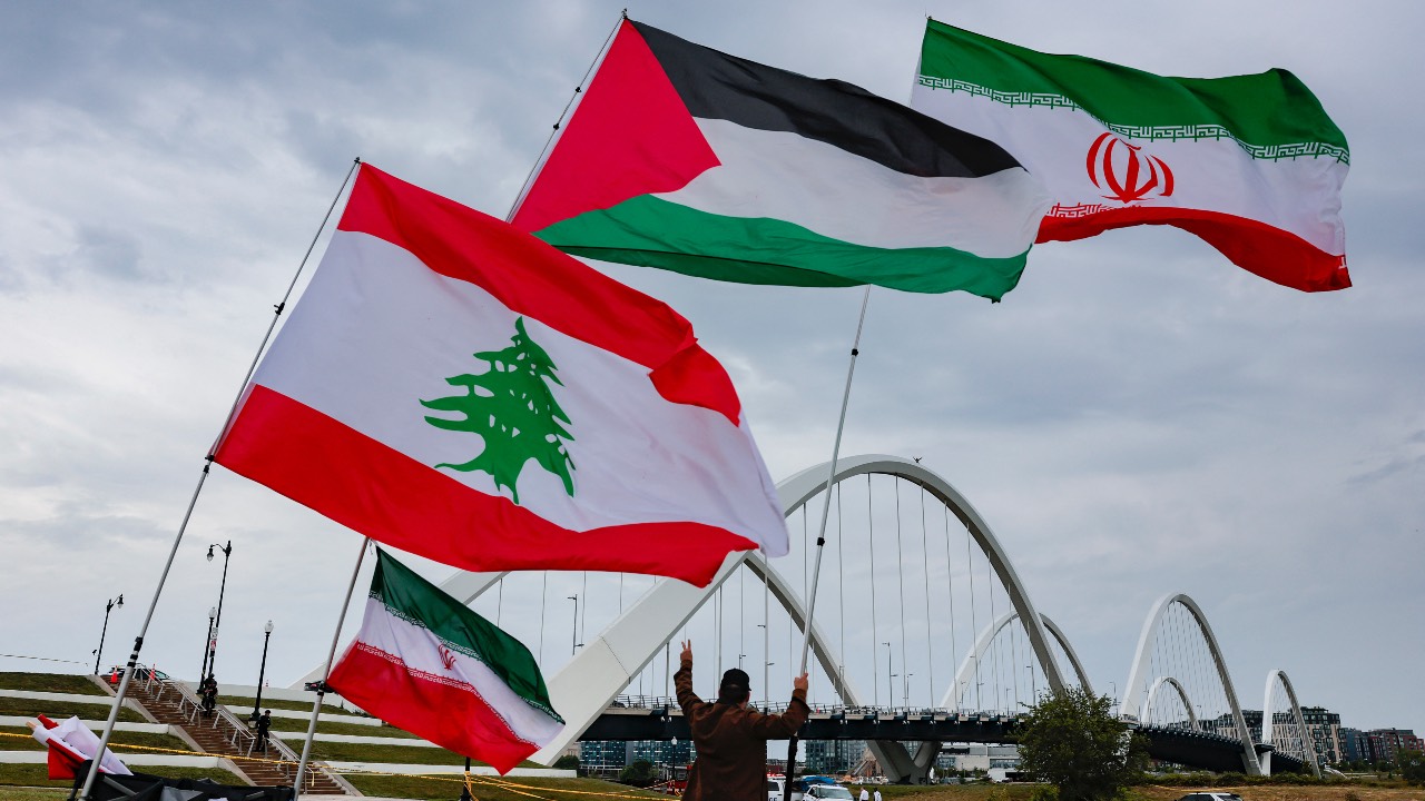 A protester against the US war in Iran gives a peace sign to protester Guido Reichstadter who stands atop the Frederick Douglass Memorial Bridge in Washington, DC. /Heather Diehl/Getty Images/AFP