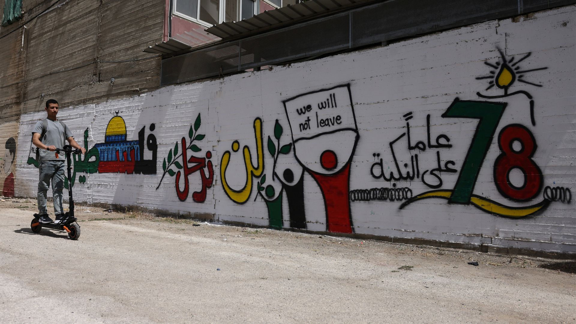 A Palestinian rides a scooter past a mural marking the 78th anniversary of the Nakba, in the Israeli-occupied West Bank city of Hebron. /Hazem Bader/AFP
