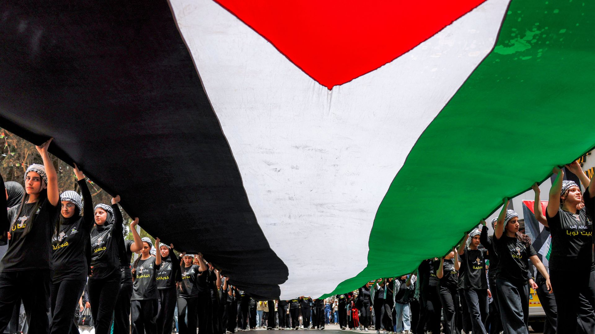 People march with a giant Palestinian flag during a Nakba protest in Ramallah this week. /Zain Jaafar/AFP

