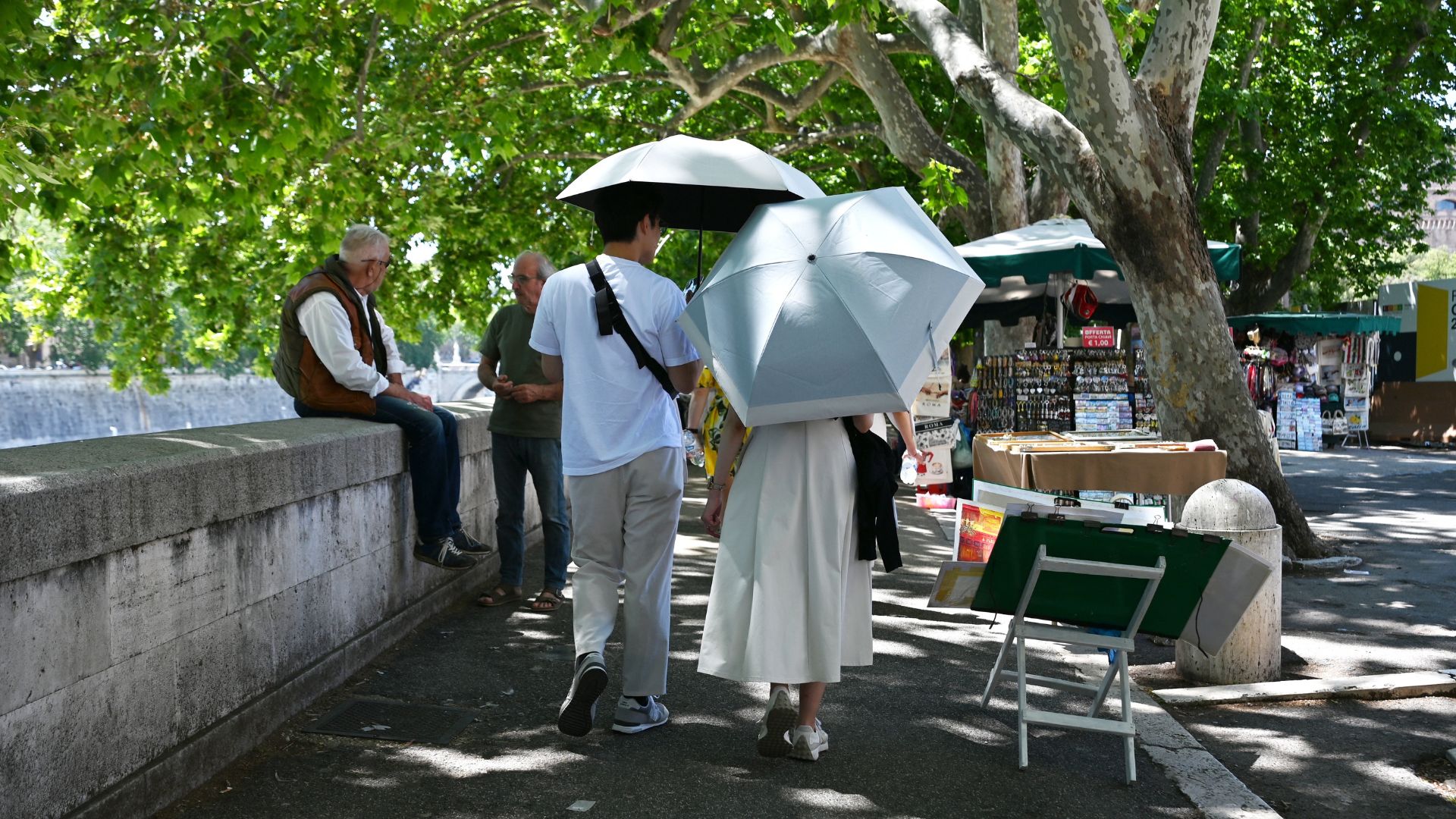 A couple hold umbrellas to shield themselves from the sun while walking along the Tiber River in Rome on May 23.
/Andreas Solaro/AFP
