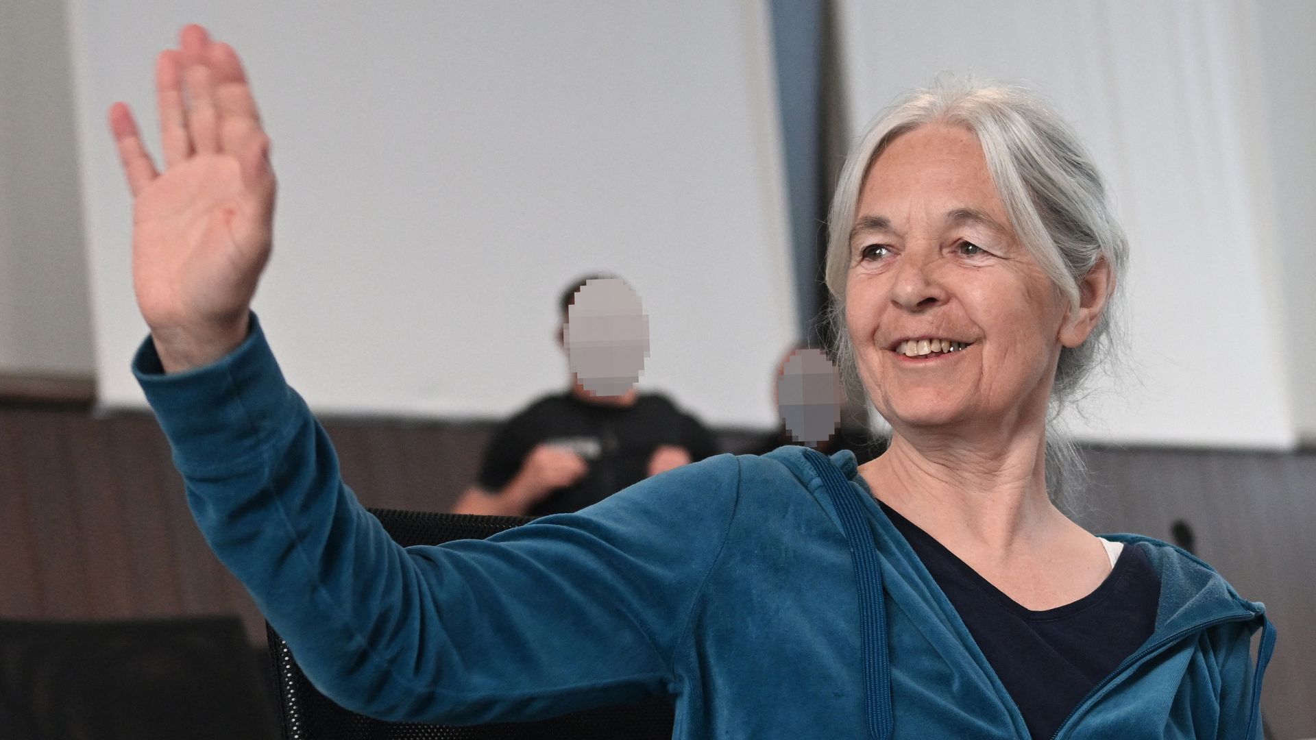 Daniela Klette waves in the courtroom of the Verden Regional Court at her trial. /Sina Schuldt/Pool