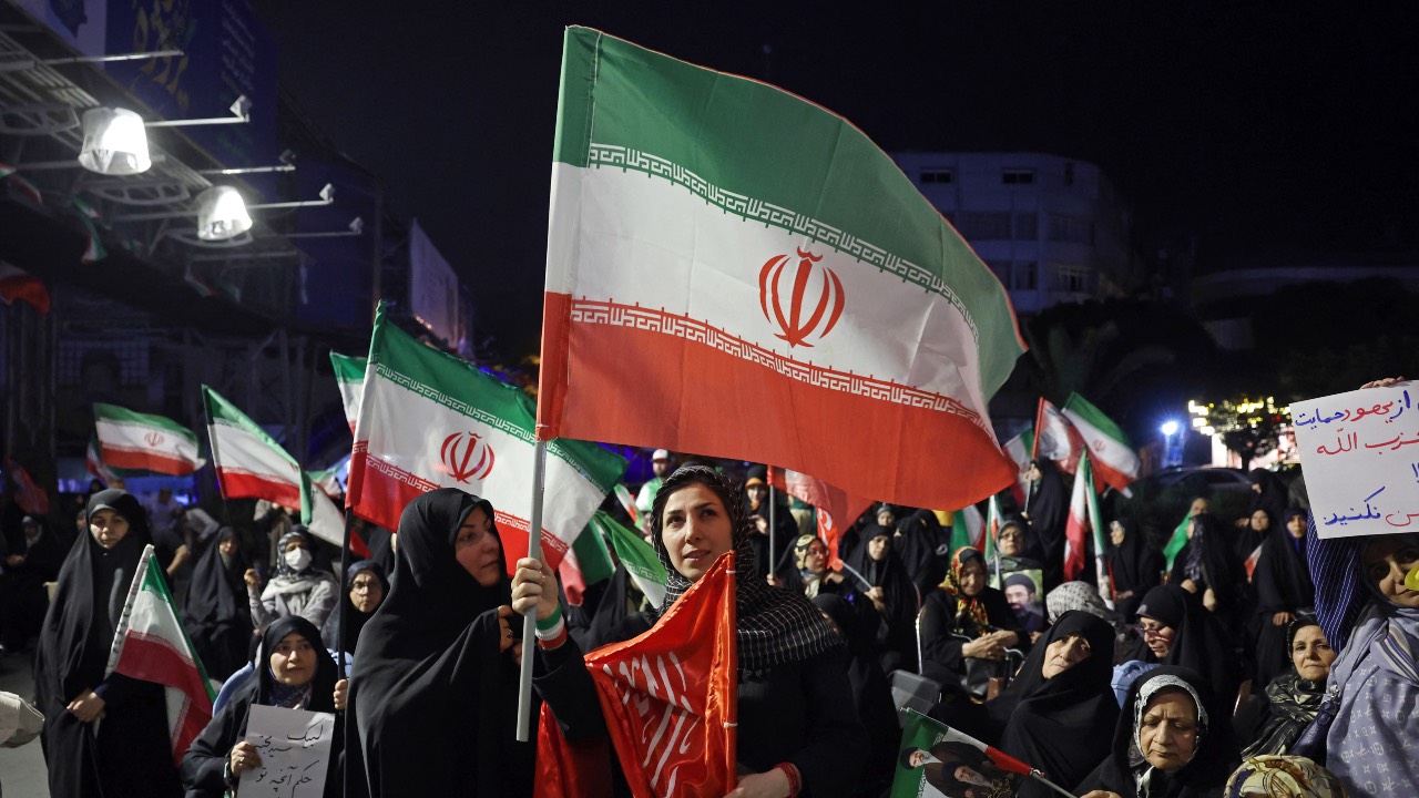 Women wave Iran's national flags during an anti-US and Israel protest in Tehran. /AFP
