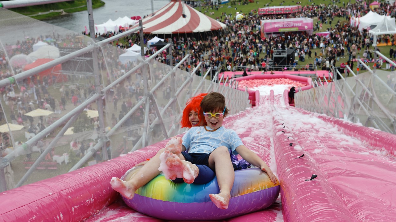 People take part in the Saltibarsciai Slip and Slide competition on an inflatable foam-covered slide during the Pink Soup Fest. /Petras Malukas/AFP