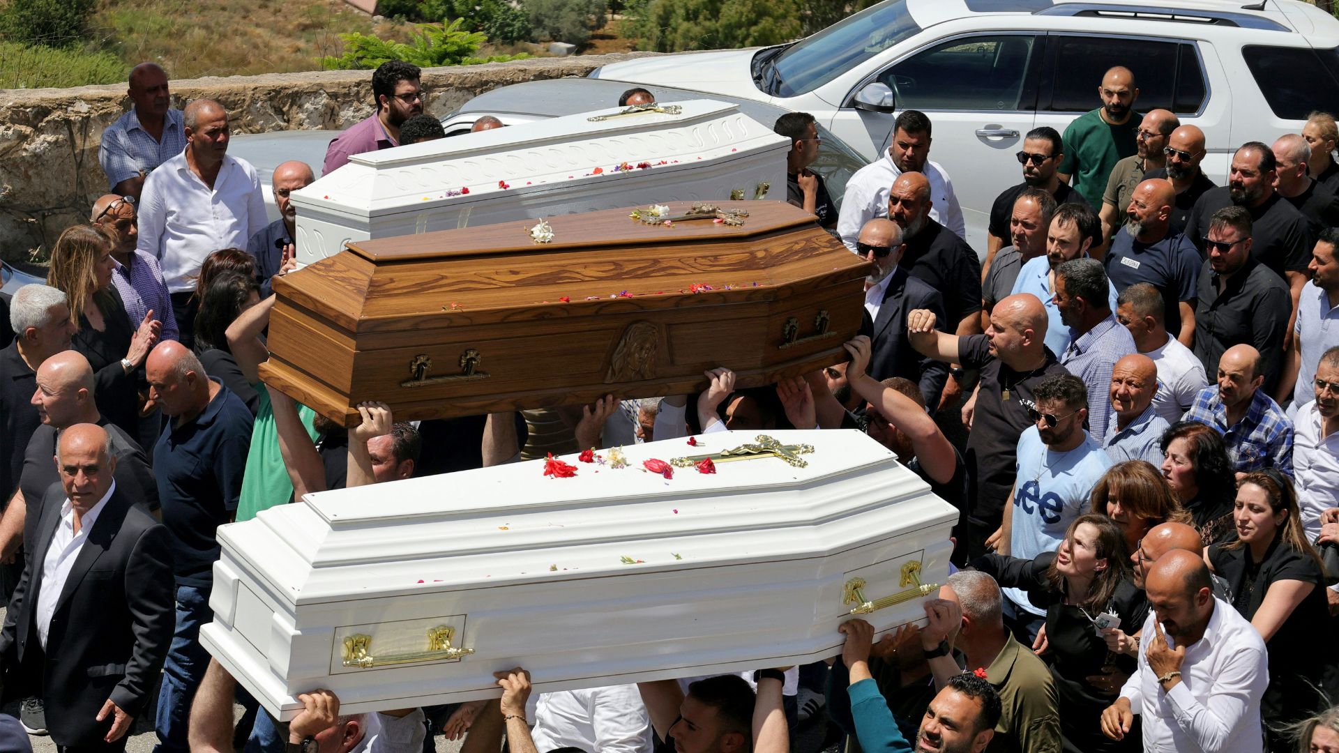 Relatives and friends of a man who was killed along with his son and daughter in an Israeli strike that targeted their car earlier this week in southern Lebanon attend their funeral in the christian border village of Qlayaa. /AFP
