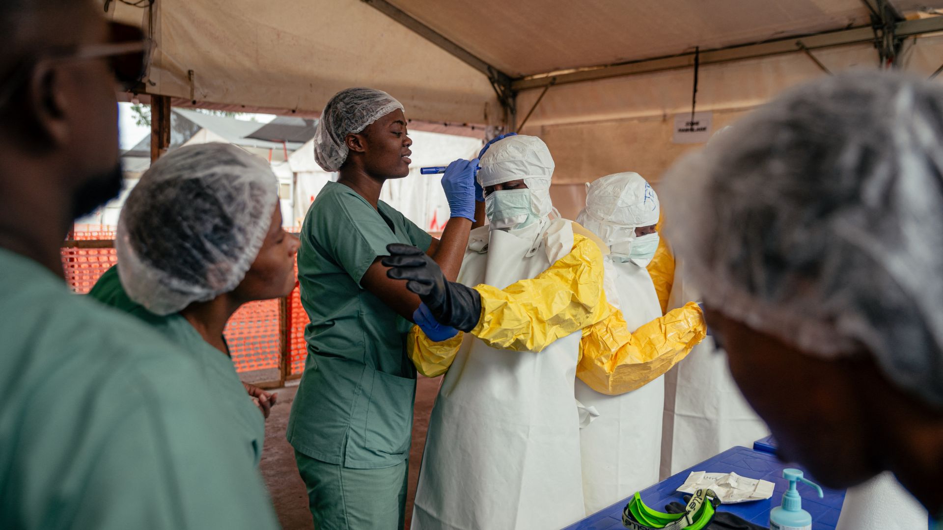 Healthcare workers put on personal protective equipment (PPE) before going to examine patients in the isolation ward during their shift at the Ebola Treatment Center (ETC) in Munigi, DRC, on June 2. /AFP