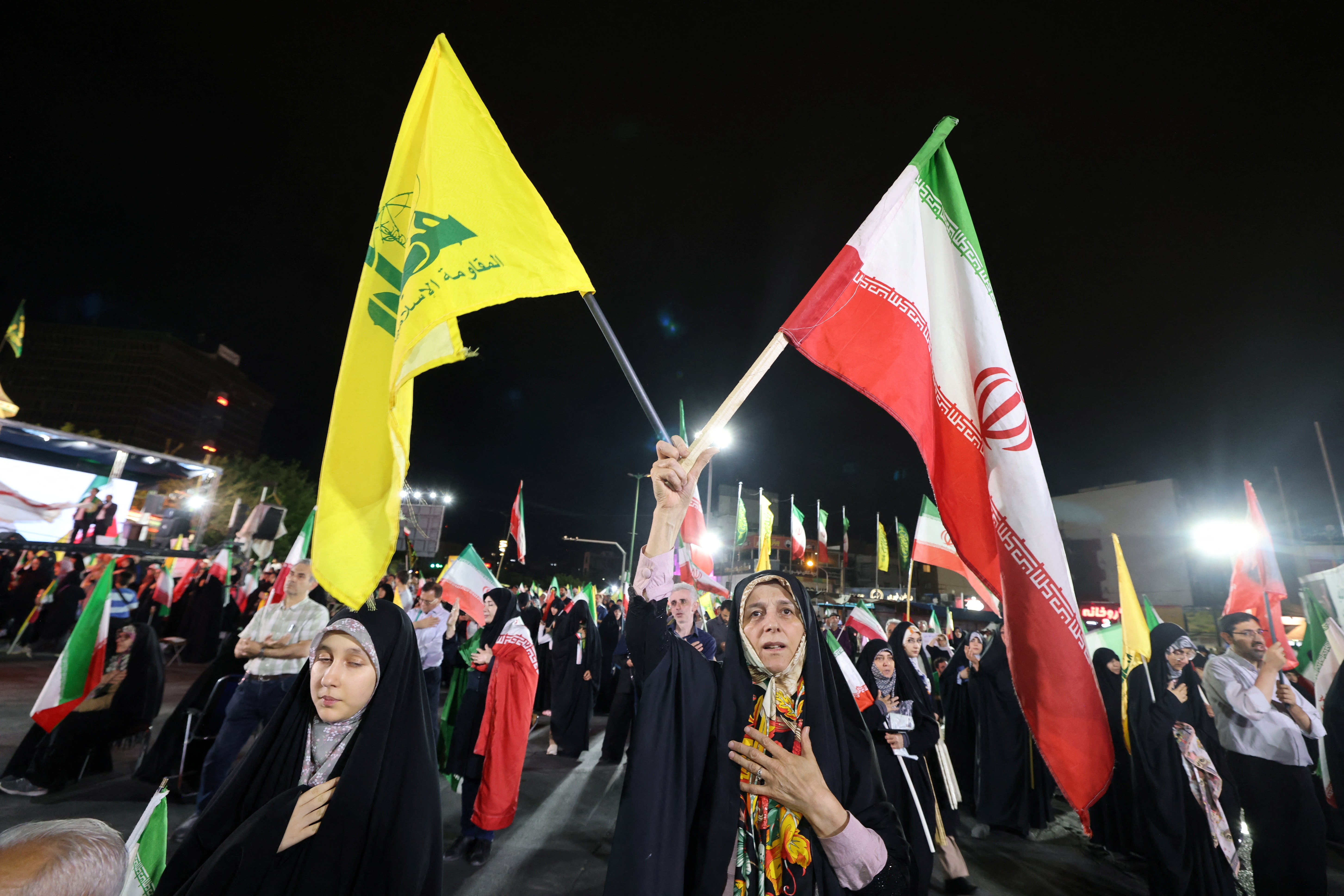 Pro-government Iranian demonstrators wave flags of Iran and Lebanon's Hezbollah movement after Israeli strikes on Beirut's southern suburbs in Tehran on June 7. /Atta Kenare/AFP
