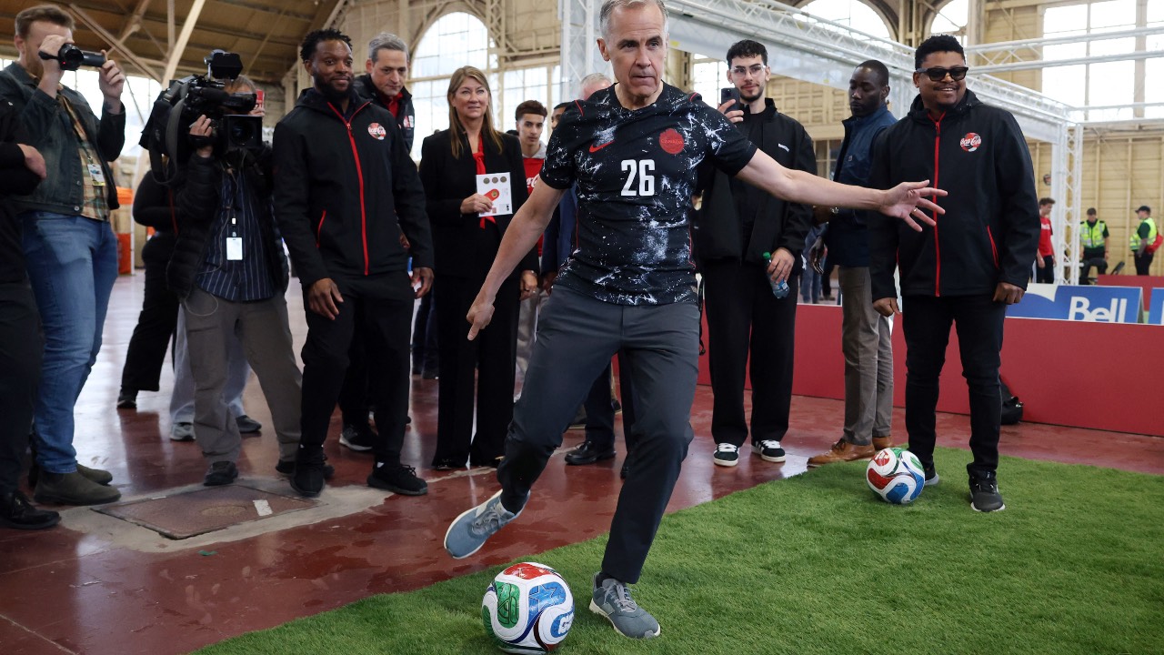 Canada's Prime Minister Mark Carney kicks a ball during the FIFA & Coca Cola World Cup Trophy Tour at Park Landsdowne Stadium in Ottawa, Canada. /Dave Chan/AFP