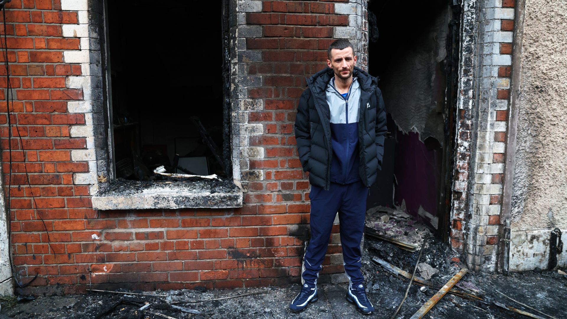 Jamie Corrie stands beside his burnt out house destroyed by rioters. /Peter Morrison/AP