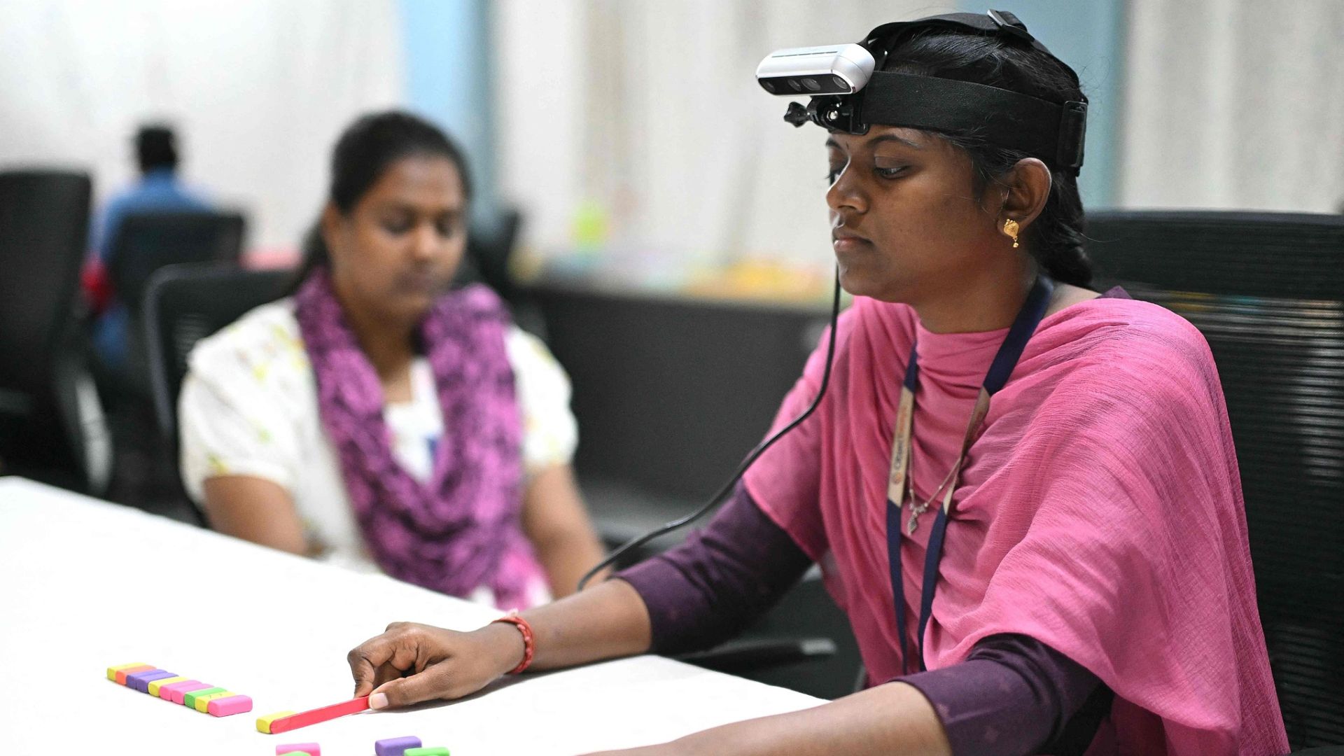 A worker wearing an RGB camera uses motion capture to record the movement of arranging colored squares in the office of AI data company Objectways. /R.Satish Babu/AFP