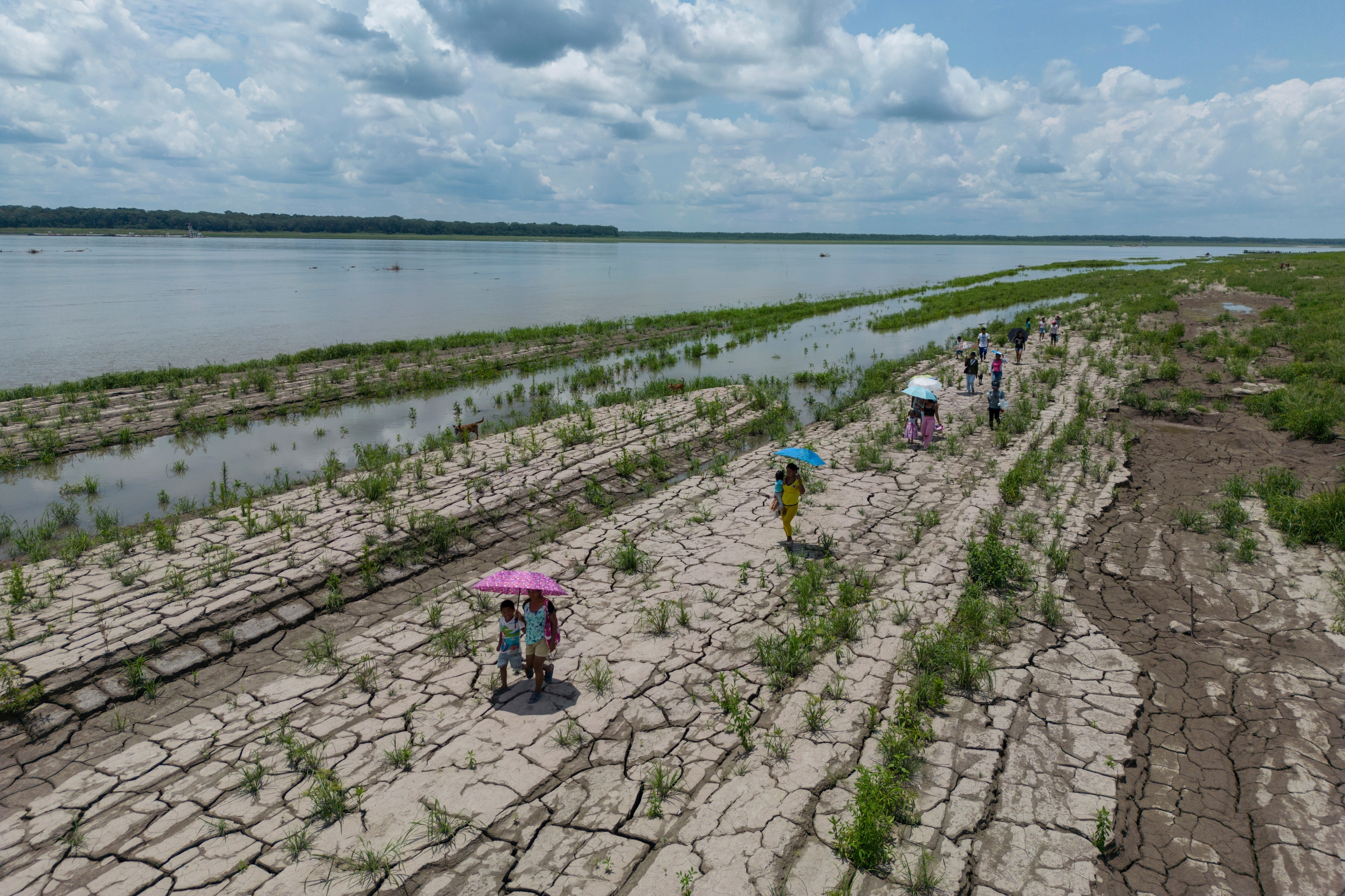 People walk through a part of the Amazon River that shows signs of drought in Santa Sofia, on the outskirts of Leticia, Colombia. /Ivan Valencia/AP