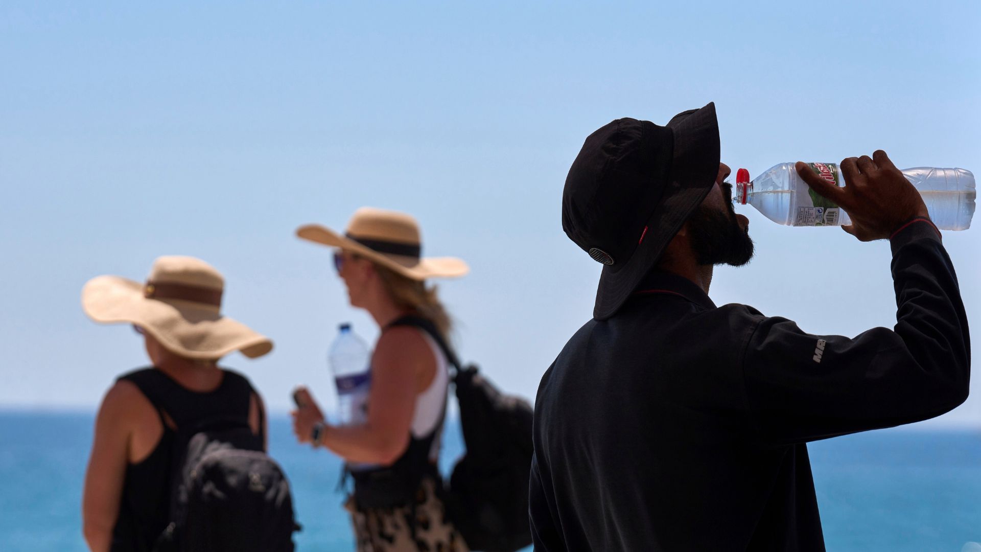 A tourist drinks water on a hot day at the beach in Barcelona, Spain. /Emilio Morenatti/AP