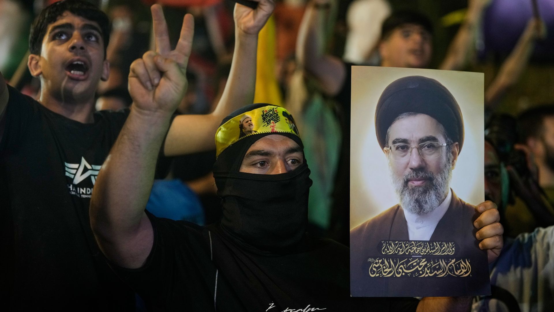 A Hezbollah supporter flashes a victory sign while holding a poster of Iranian Supreme Leader Mojtaba Khamenei during a gathering against the U.S.-Israeli military operation with Iran and its allies in Dahiyeh, Lebanon. /AP Photo/Bilal Hussein