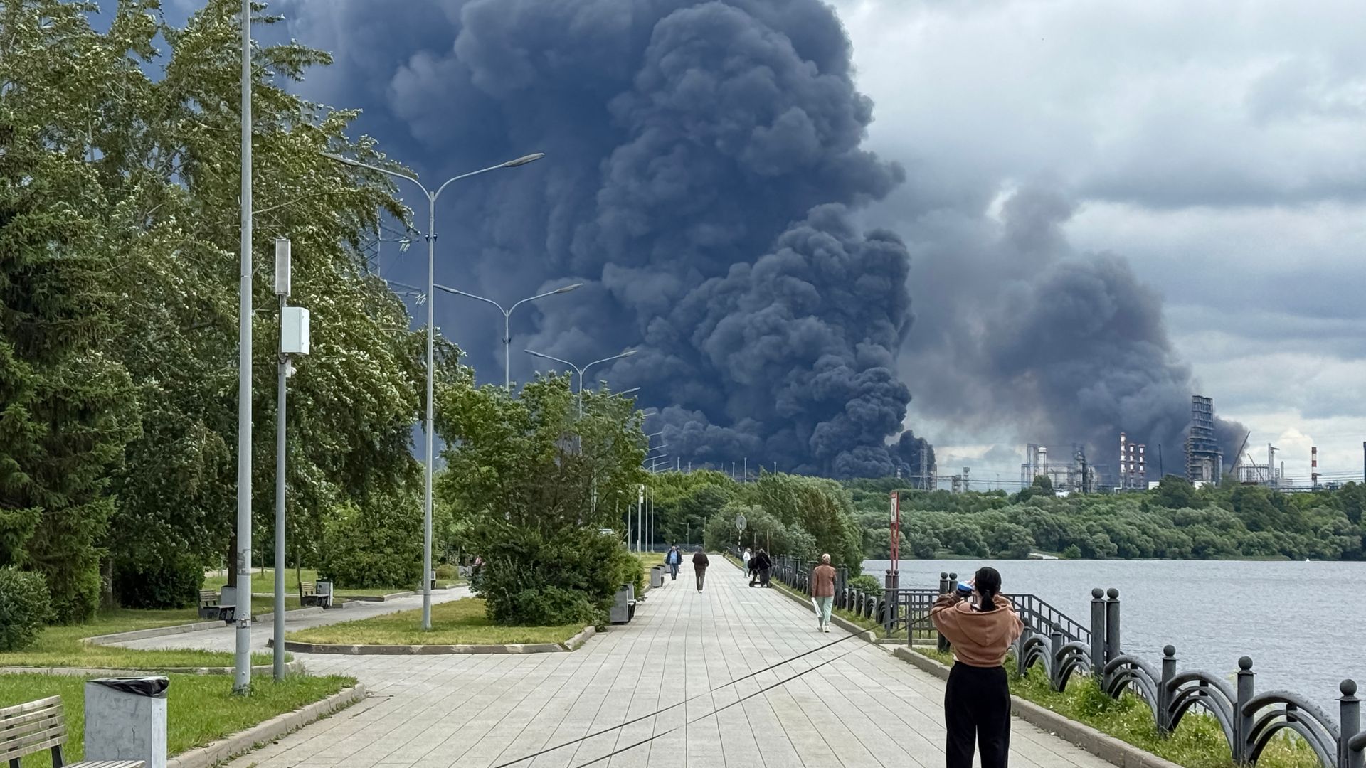Residents stop to take pictures of the smoke pouring out of the Kapotnya refinery not far from Moscow's city centre. / AfP.